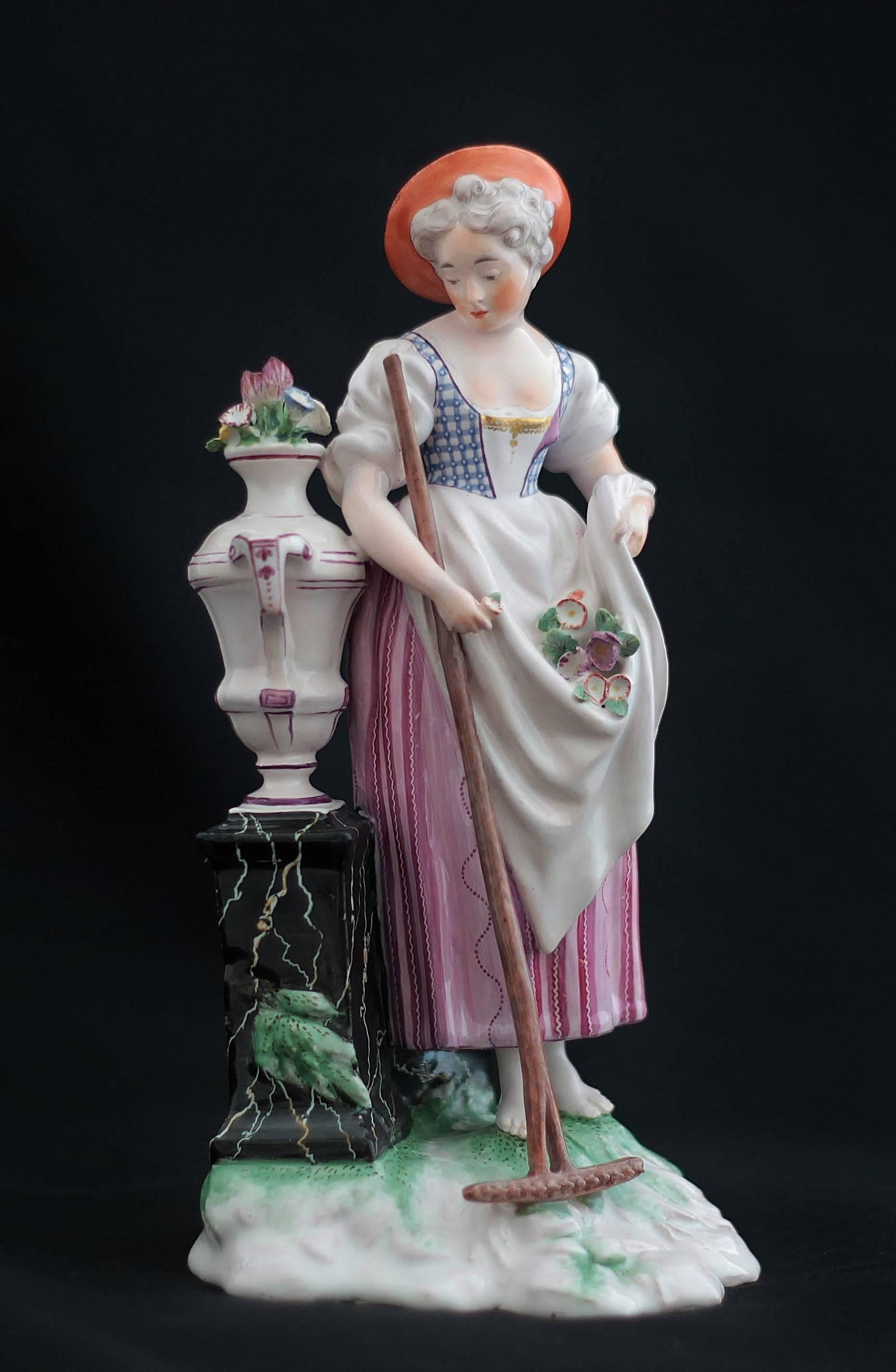 Figure of Niderviller faience representing a young woman holding flowers and rake near a vase put on a stele in false marble,
18th century.
Measures: Height 22 cm, width 11 cm, depth 10.4 cm.
Handle of the rake restored, chips at the hat and at