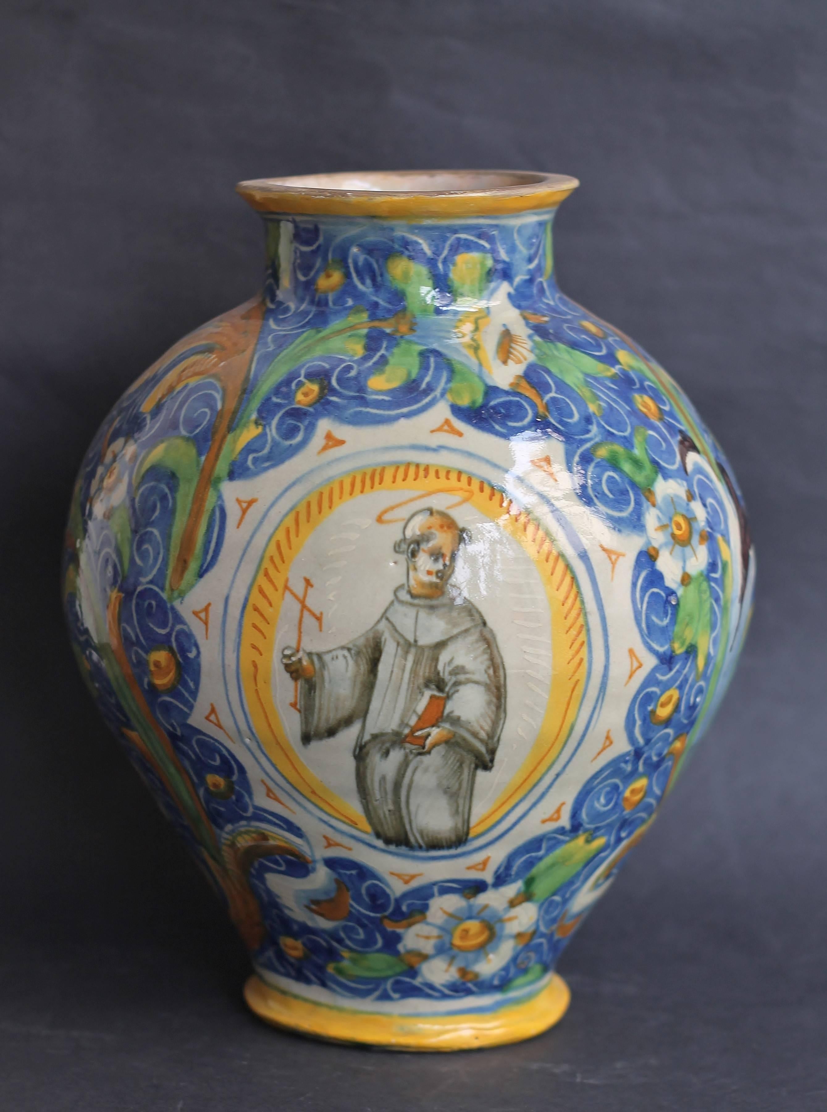 Ovoid vase in Majolica with polychrome decoration the broad rinceaux one flowered on blue bottom and of an oval cartouche representing Saint François with the bible in the left hand and a cross in the right hand, the “perfect Christian”. It’s the