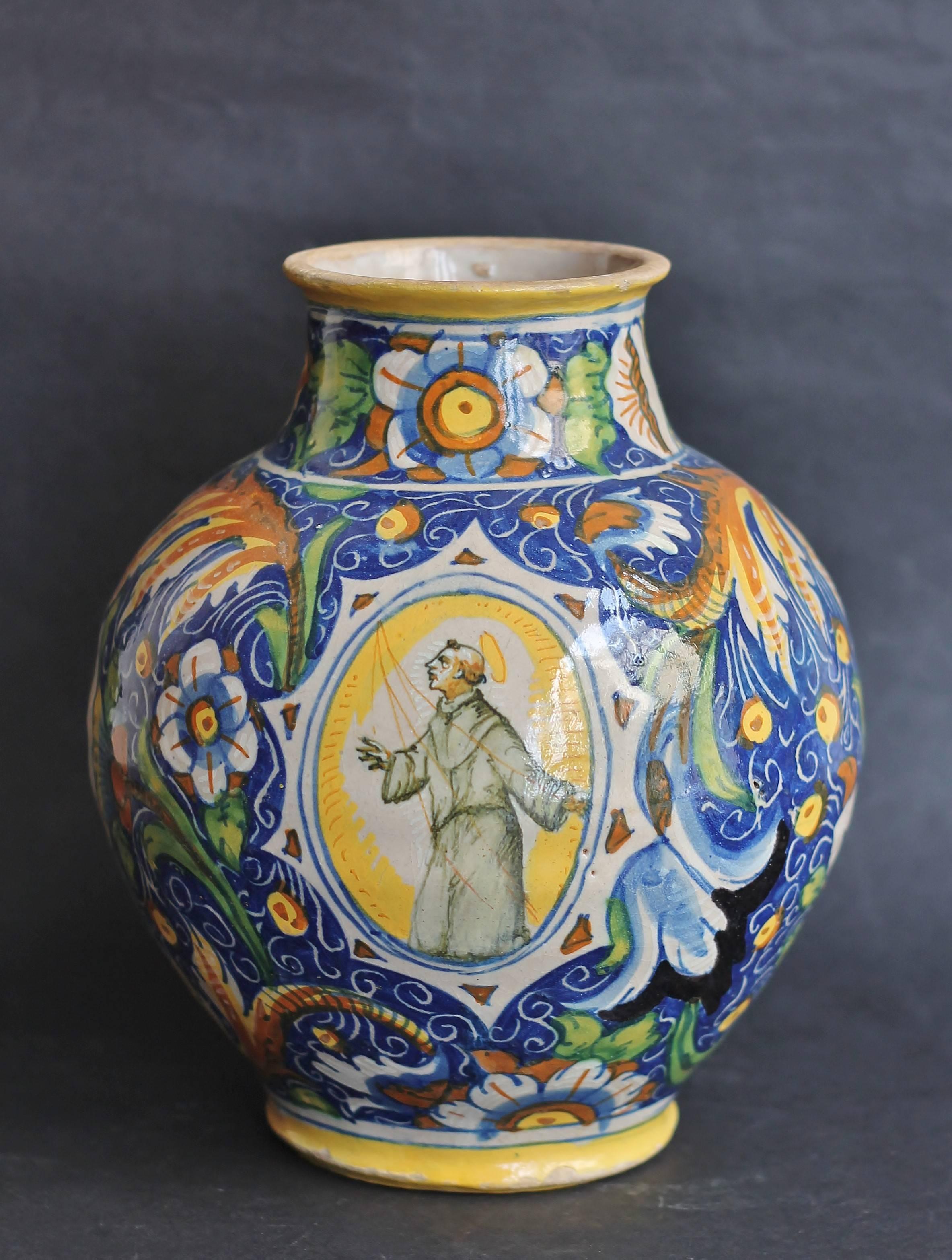 Ovoid vase in majolica with polychrome decoration the broad rinceaux one flowered on blue bottom and of an oval cartouche representing Saint François with the face and the hands turned skyward. It’s the perfect Christian. It’s the Saint the most