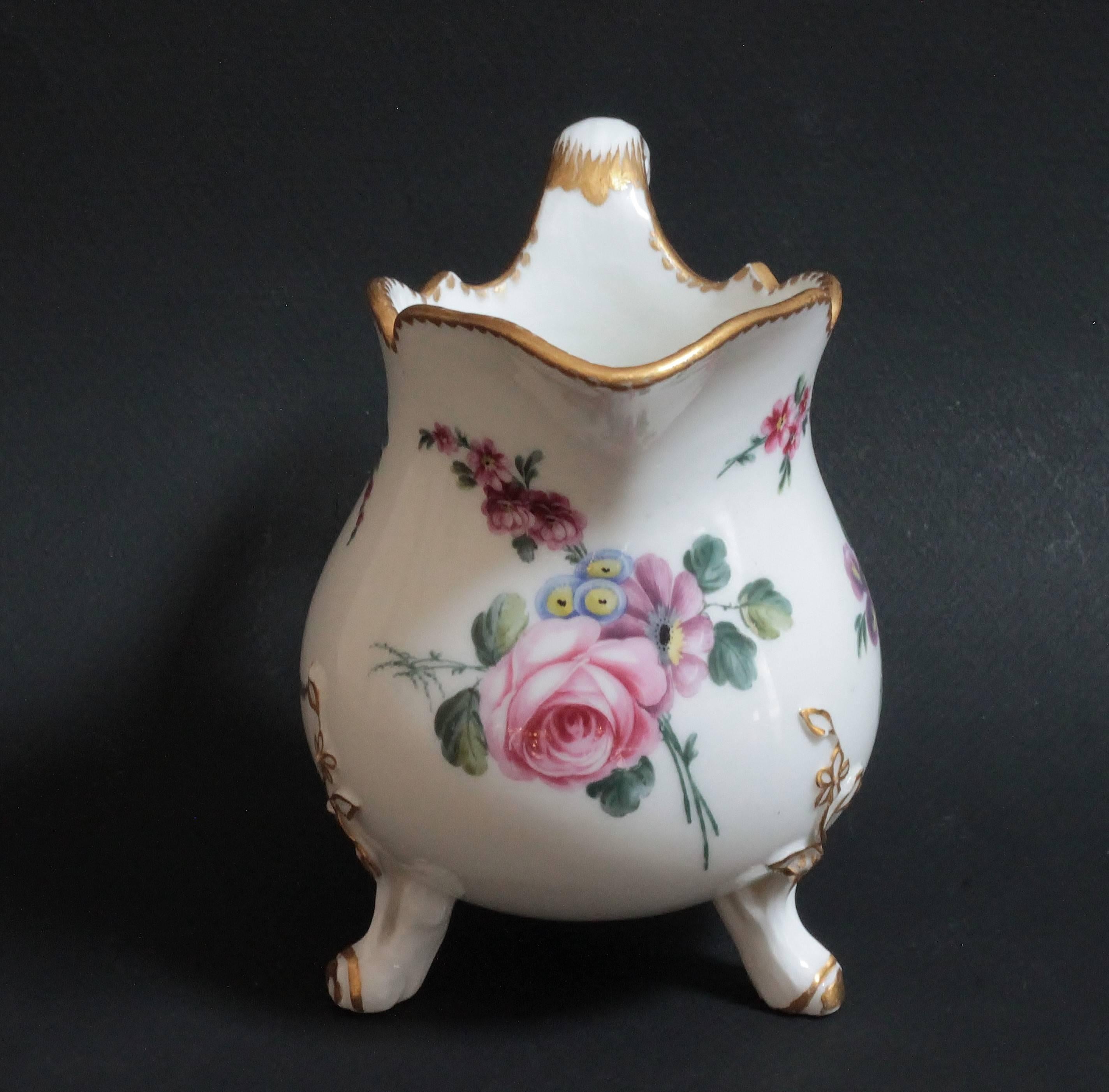A Sevres porcelain milk jug painted with loose floral bouquet, three gold branches on feet and around handle. Marked in blue under the milk jug with interlaced LL monogram and o for 1767 date-letter, and a sun for the painter De Ville or N-L Petit.