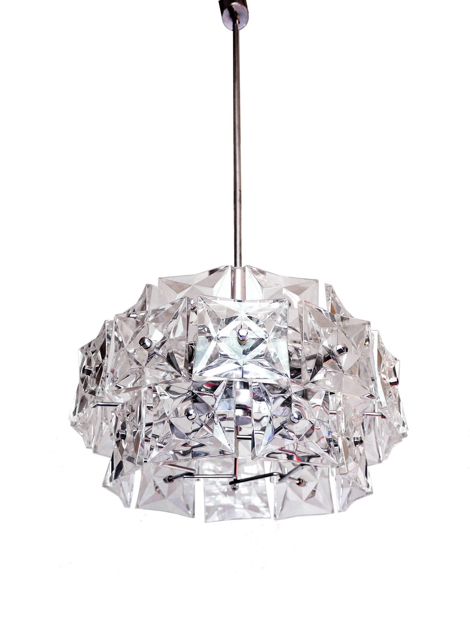 Three-tier chandelier with sculptural faceted crystals and chrome-plated frame made by Kinkeldey, Germany in the 1960s. 

Lighting: takes one big Edison E27 base bulb and twelve small Edison E14 base bulbs. 
The bar is divided and can be shortened