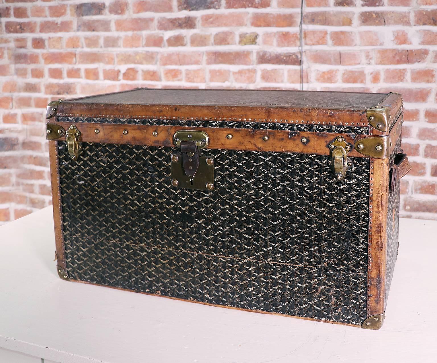 A splendid E. Goyard Aîné shoe trunk in chevron canvas with a massive brass lock and hasp and leather handles with their original patina and coating. Monogrammed ‚M‘ on the side. The interior inserts or partitions are missing.
The lock of the trunk