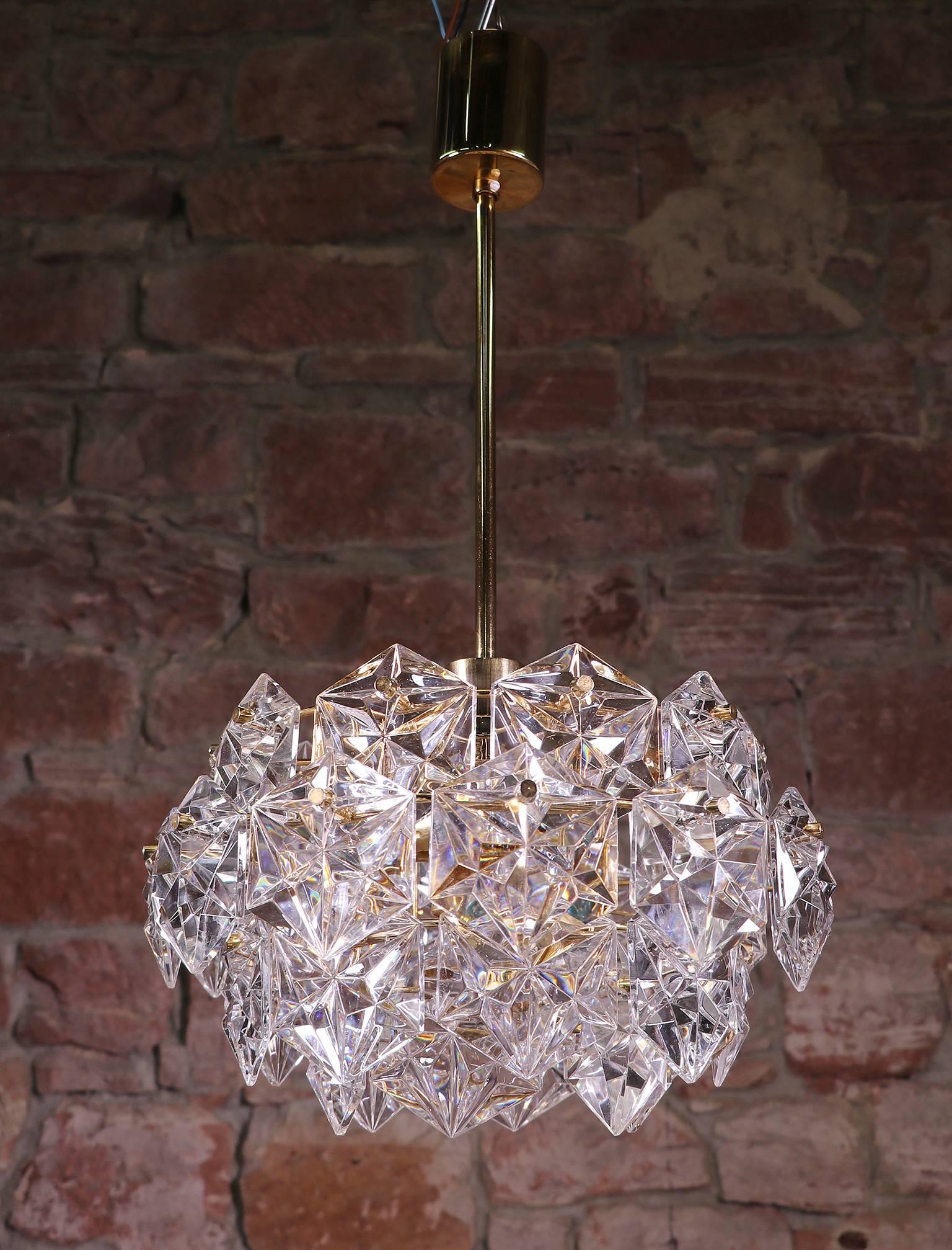 Four-tier chandelier with sculptural faceted crystals and gold-plated brass frame made by Kinkeldey, Germany in the 1960s.
The lamp takes one large and three small Edison base bulbs.