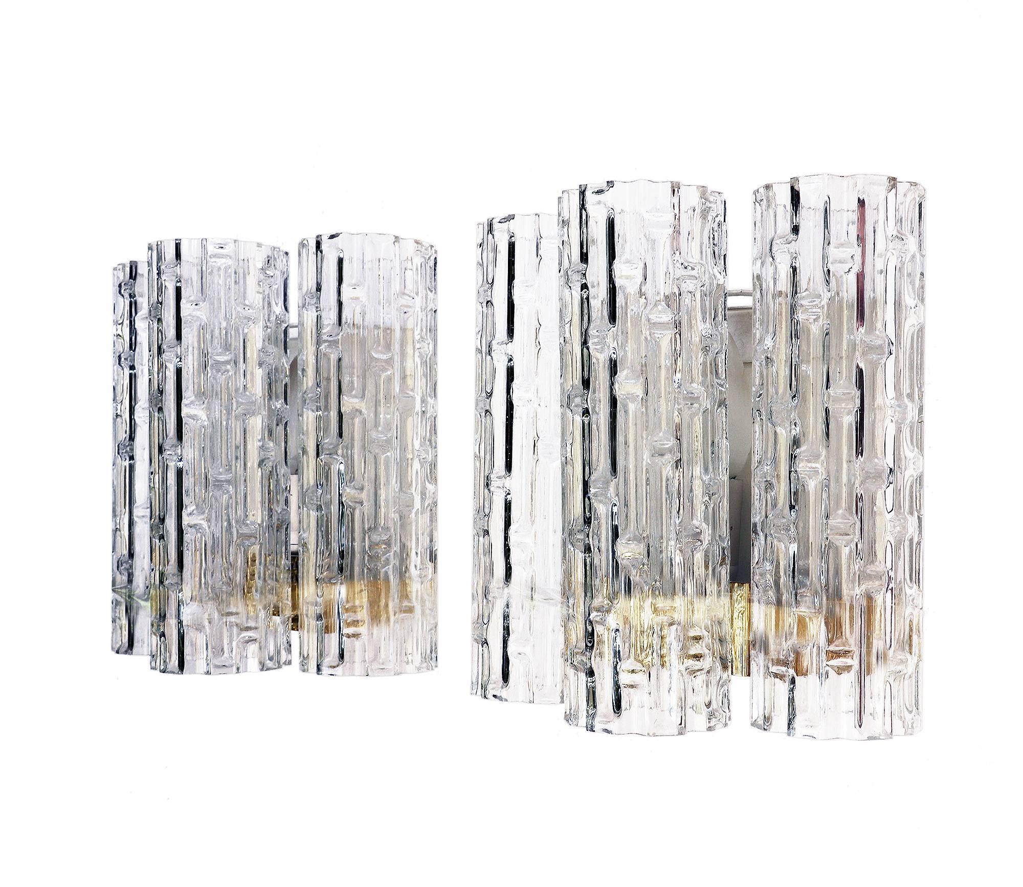Elegant pair of mid century wall sconces with large textured Murano glass tubes on a metal frame. Designed by Wilhelm Braun Feldweg. The back-plate is made of white lacquered metal and polished brass. With this sconces you make a clear statement in