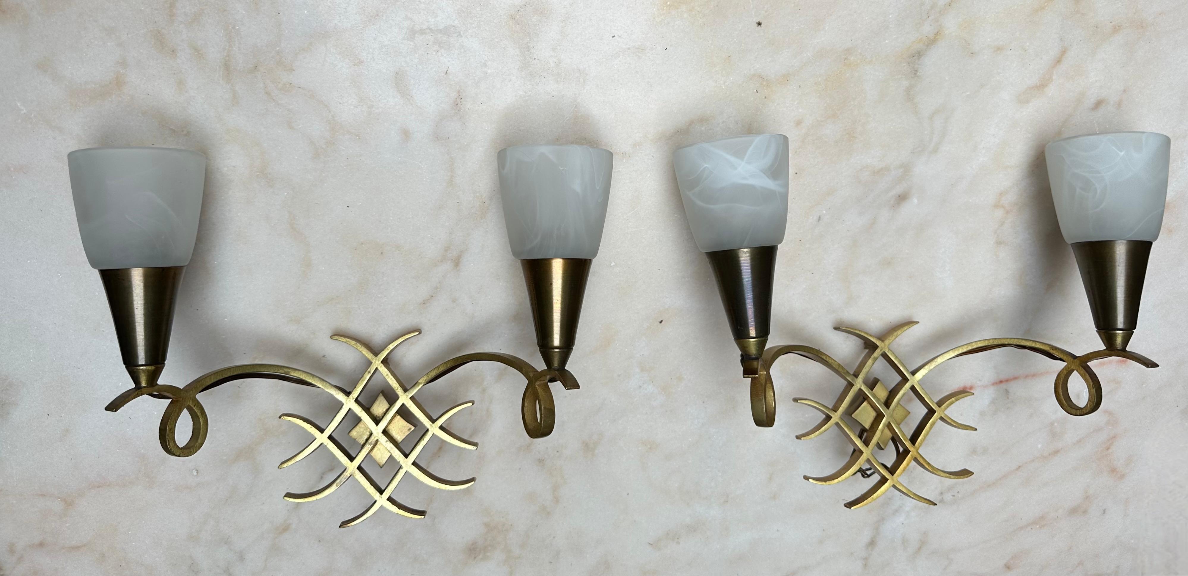 Stylish pair of bronze, brass wall fixtures with vintage glass shades, with later glass shades.

This striking duo of French wall sconces, attributed to the iconic Jules Leleu, embodies the grace, precision, and timeless elegance that defines high