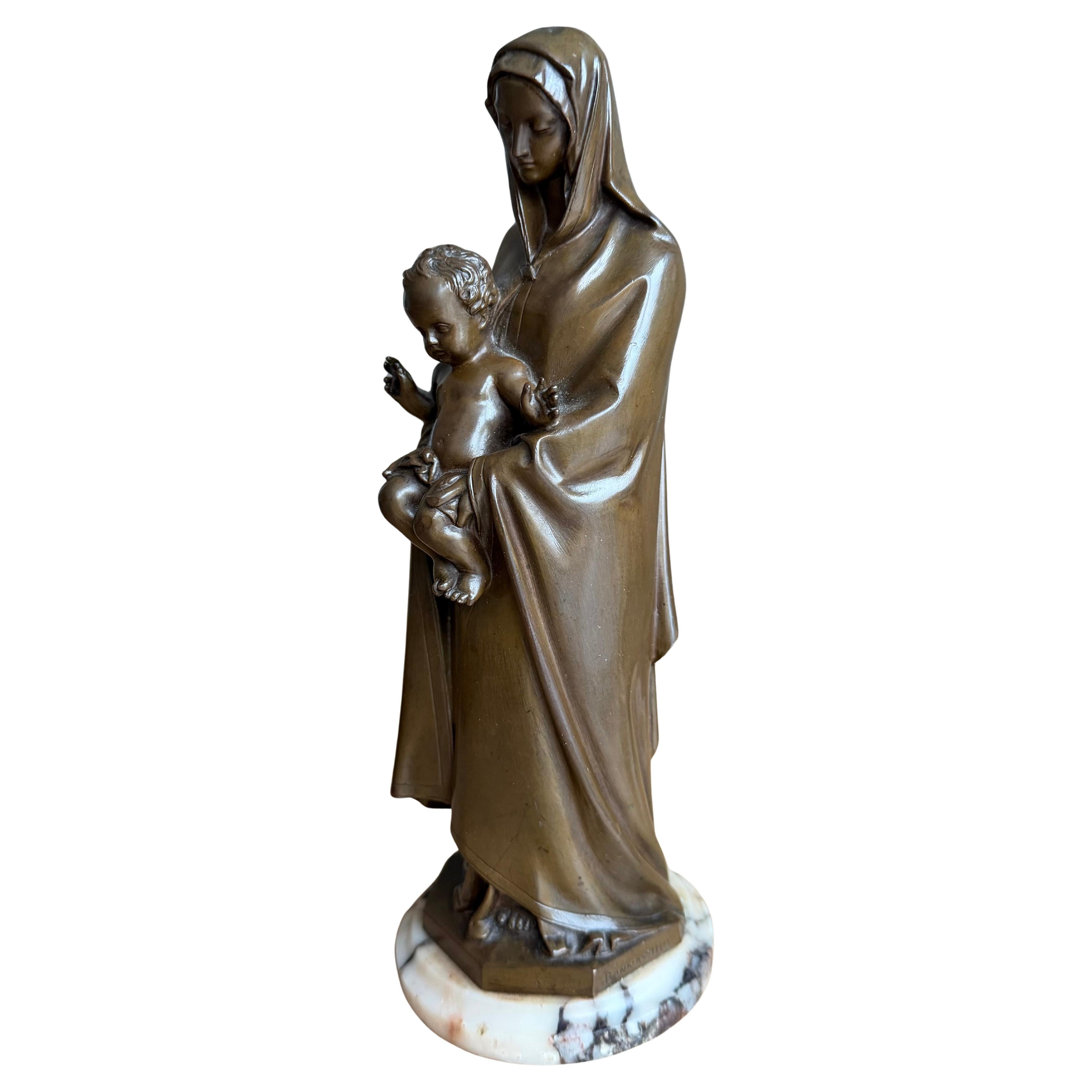 Scultura religiosa antica in bronzo pregiato di Maria e del Bambino montata su una base di marmo