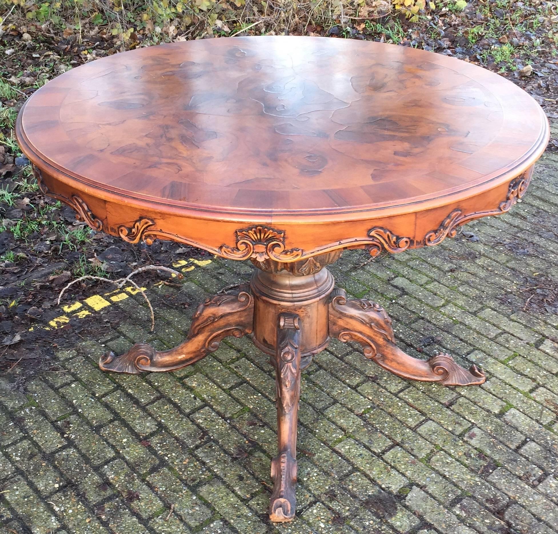 Handcrafted and impressive Mid-Century wooden center table.

This round table is beautifully decorated with a rich variety of carved elements and the top is inlaid with stunning burr walnut. The base with the cabriole legs is all hand-carved and all