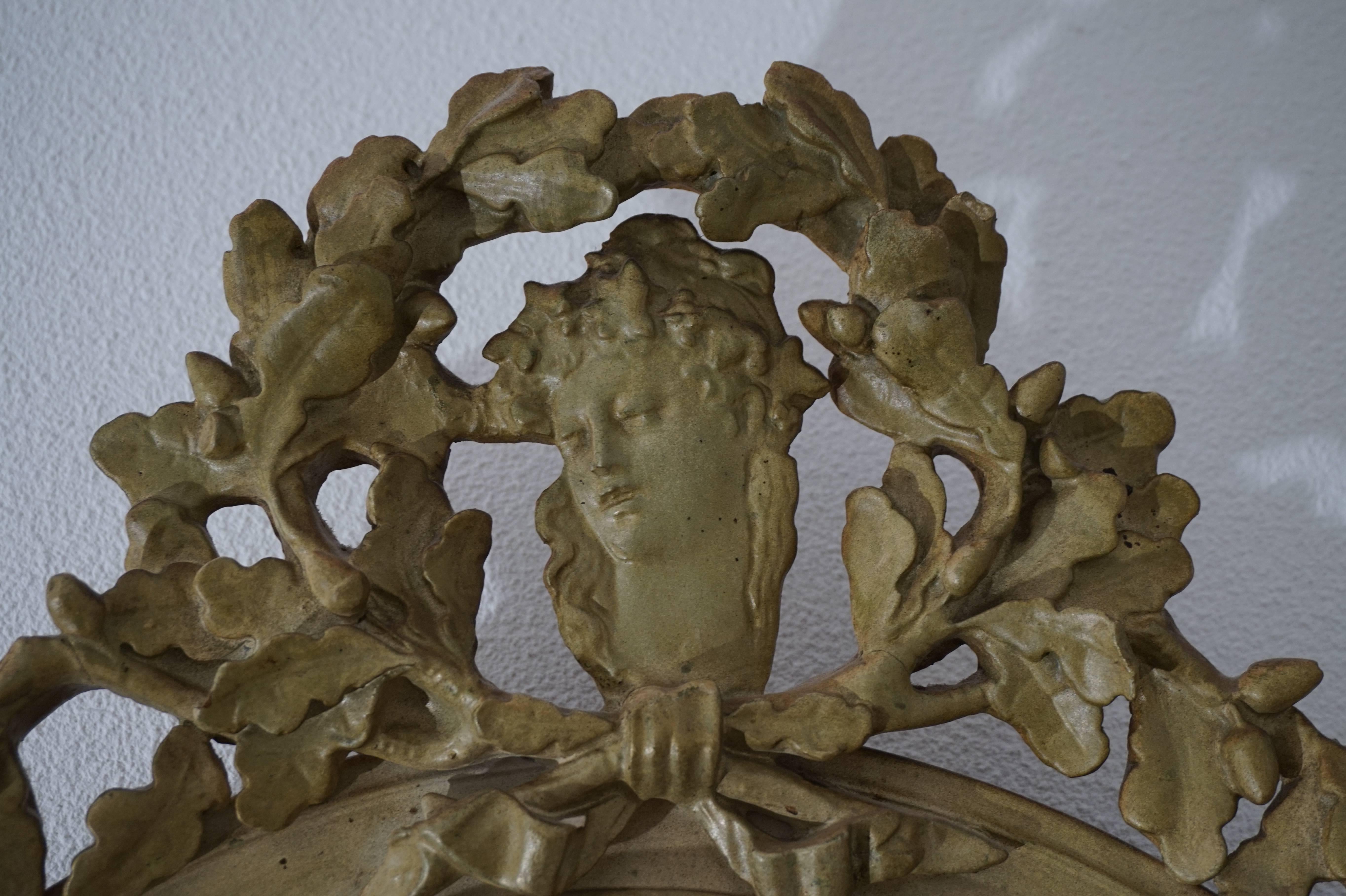 Rare and practical size, antique mirror.

This late Victorian, beveled mirror is in very good and original condition. The oak leafs atop are shaped like a royal crown. In the middle of this stylized crown is a beautifully carved image of a young