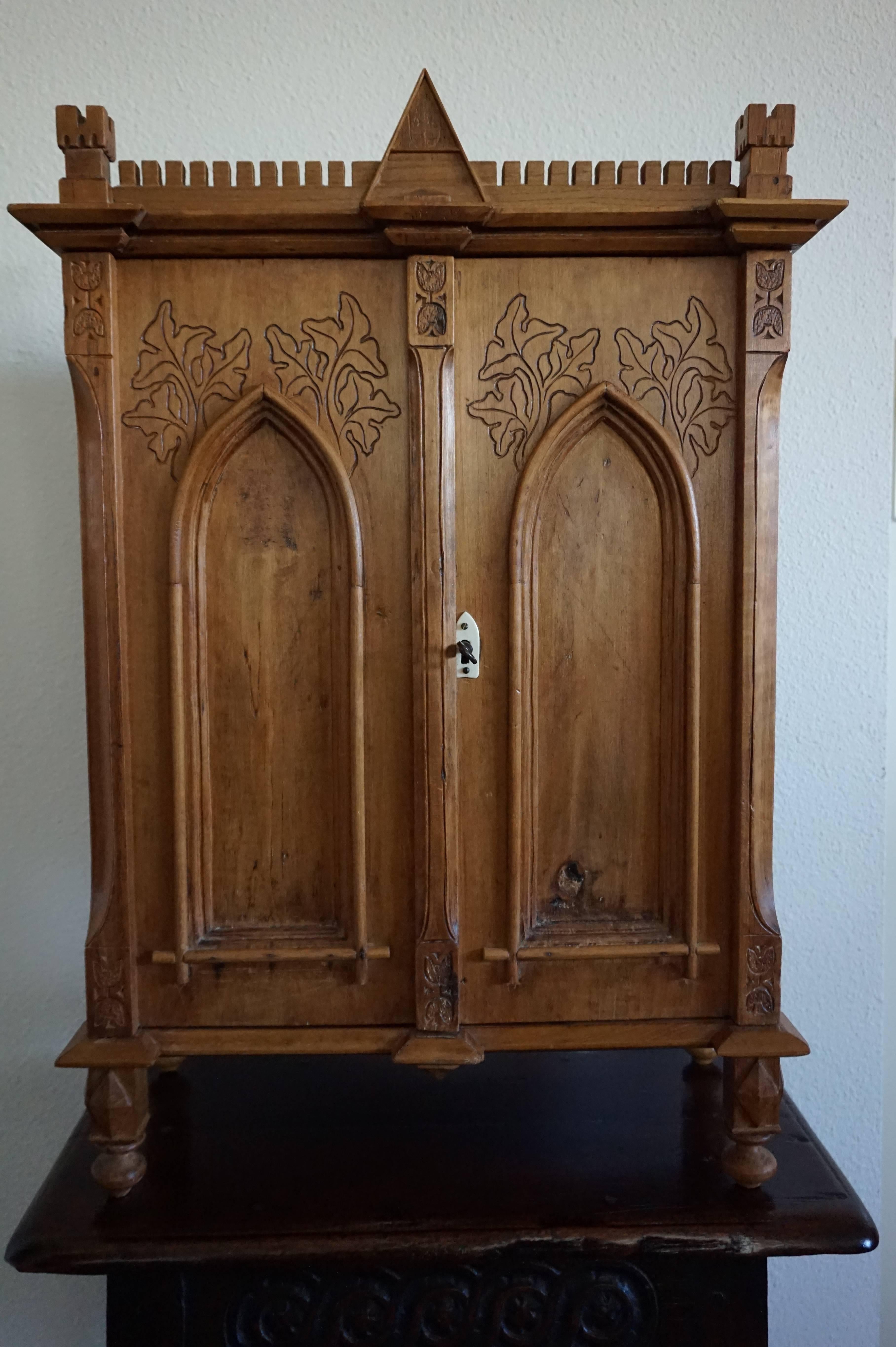 Unique miniature that can also be used as a wall cabinet.

This handcrafted Gothic Revival miniature cabinet has the shape of a medieval castle with towers at all corners, a crest in the middle (on top) and also panels in the front and on the sides