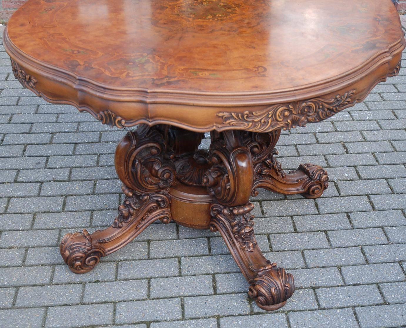 Stunning wooden table top with marquetry inlay.

This impressive, vintage wooden centre table is entirely handcrafted. There is a rich variety of carved elements in the stunning base. These cabriole legs are all hand-carved and all made of solid