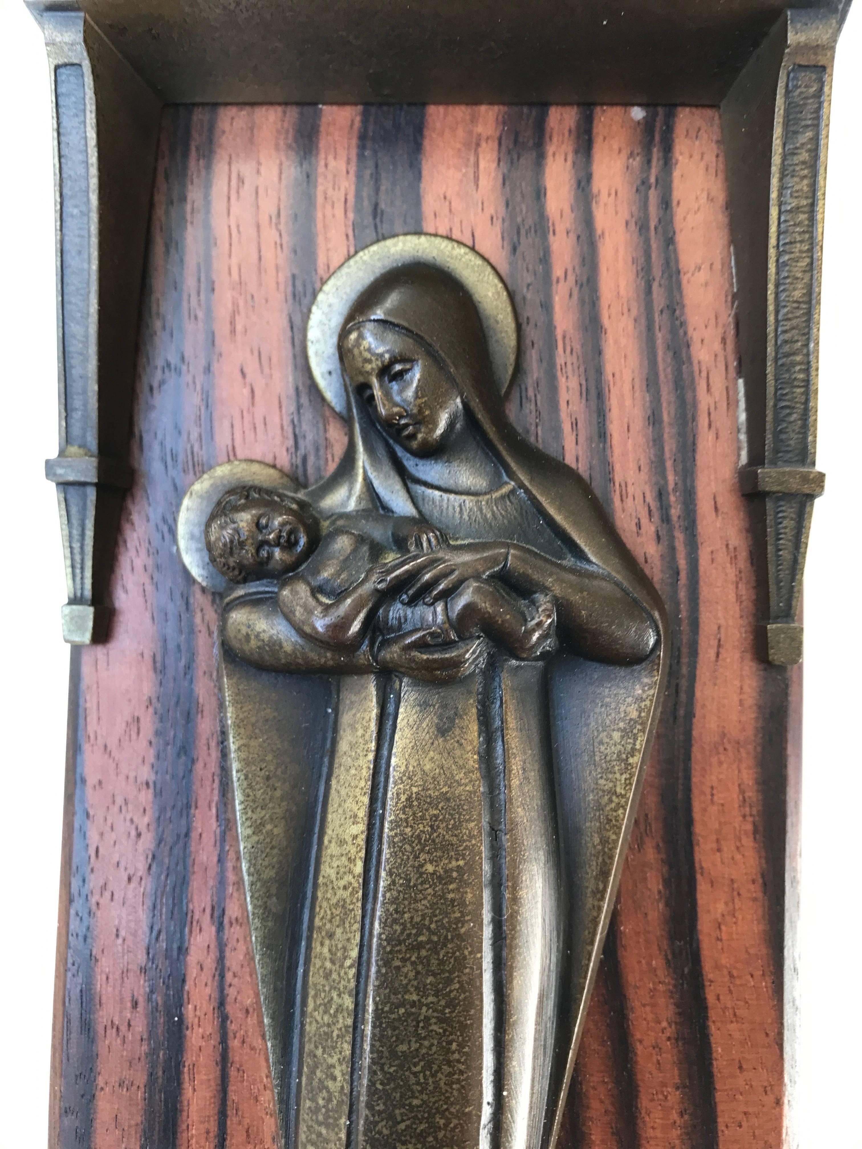 Stylish and meaningful religious work of art.

This religious work of art dates from the 1920s or 1930s. It is shaped like a chapel and it could very well originate from one. This small but impressive wall plaque is made of bronze and Macassar ebony