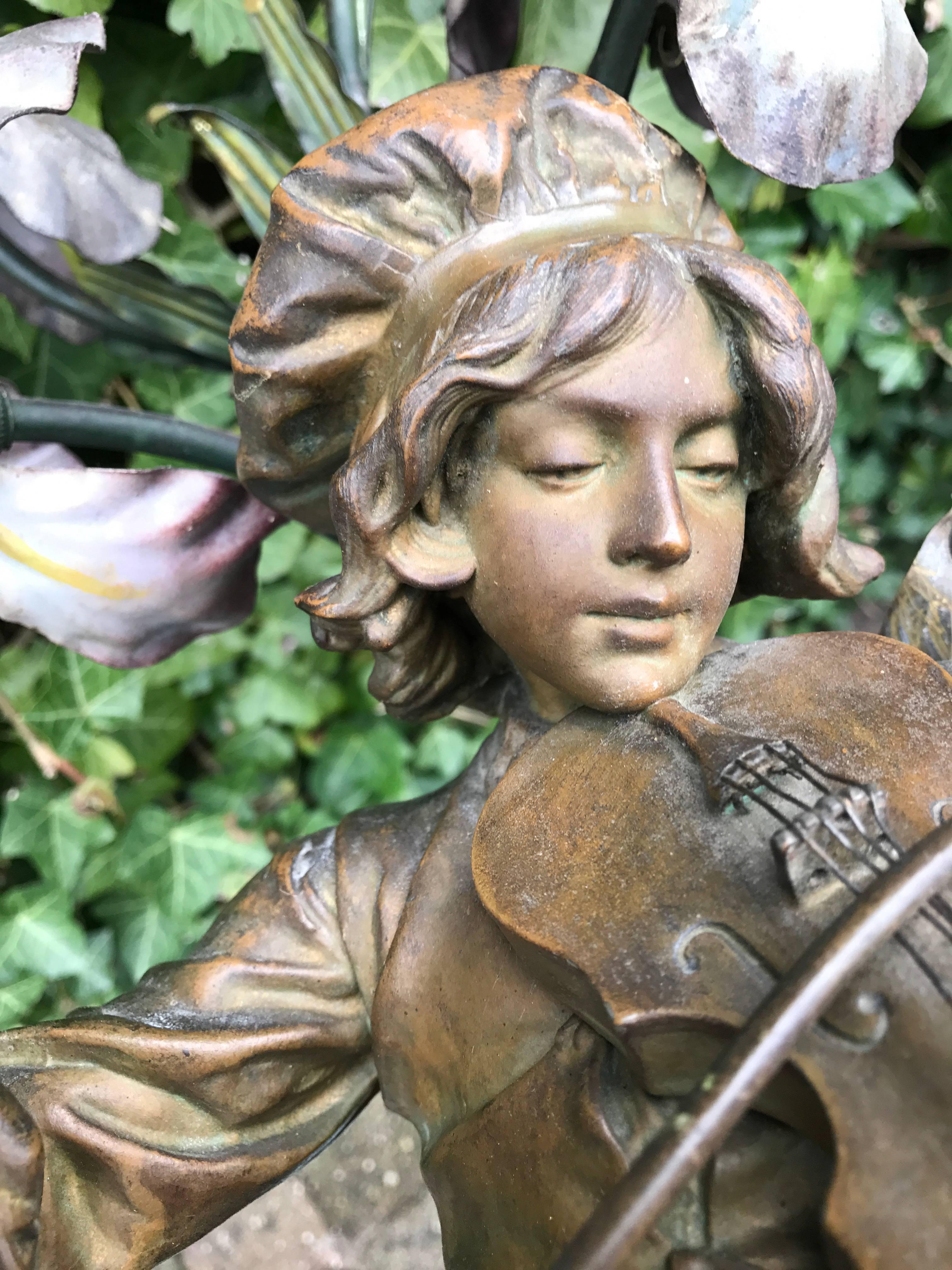 Lovely four-light table lamp with musical theme.

This antique and sculptural French lamp features a boy who is tuning his violin in a floral setting. The natural and realistic poisture of this focused boy shows the craftsmanship of the maker.