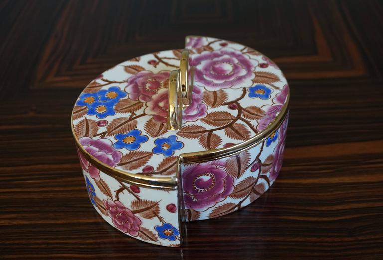 Stunning geometric design porcelain box by Chevalier.

If you are an Art Deco enthousiast then you will immediately recognize this pure Art Deco design. The hand-painted flower motifs are as if they were enameled and they by Raymond Chevalier. This