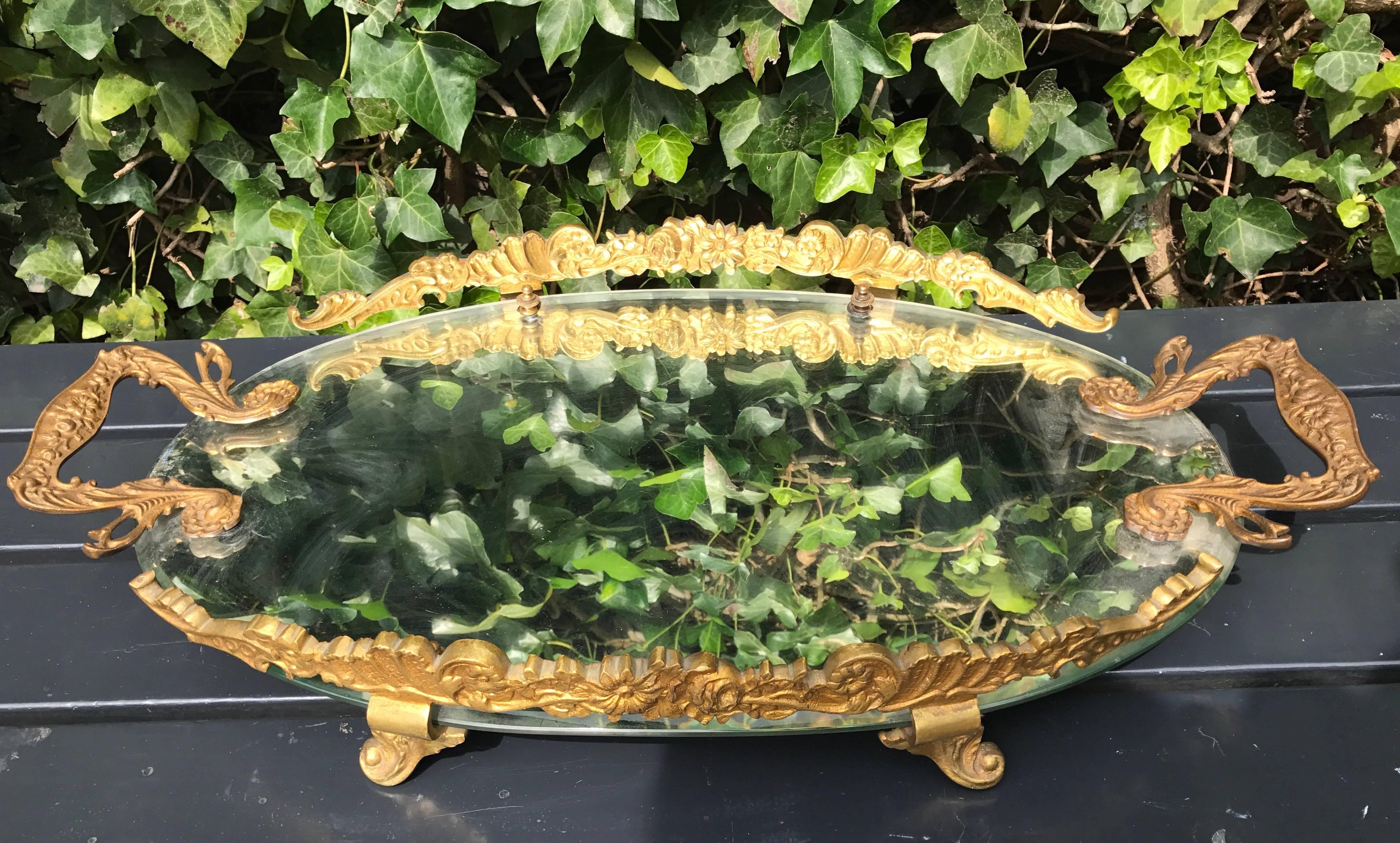 Highly stylish and in great condition. 

This beautiful tray comes with intricate details and an antique, oval mirror forming the base. The thick and heavy bronze ornamentation makes this rare tray extra impressive and a joy to look at. It sits on