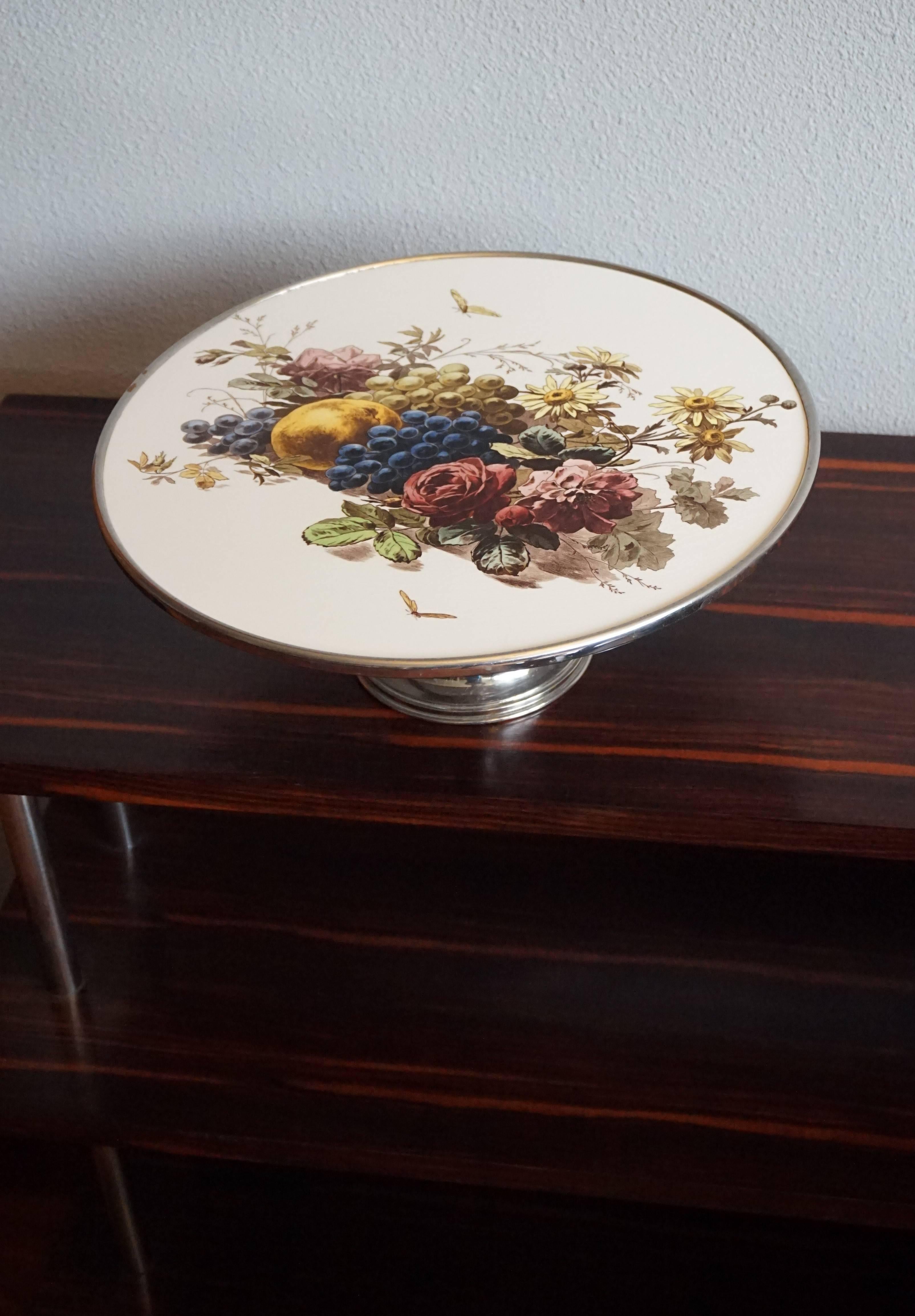 Handcrafted 1920s pie stand with beautiful decor.

This stylish and decorative pie stand from the 1920s is in very good condition. The shape of this wonderful stand is a joy to look at and the stunning decor of fruits and flowers really takes it to