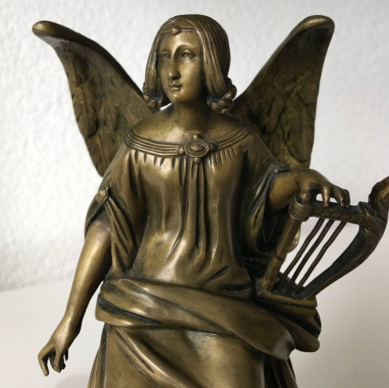 19th century, bronze sculpture mounted onto a wooden base.

This small and rare bronze work of religious art shows the figure of an angel with a harp. The serene face of this pretty angel and the beautifully draped cloth around her body are an