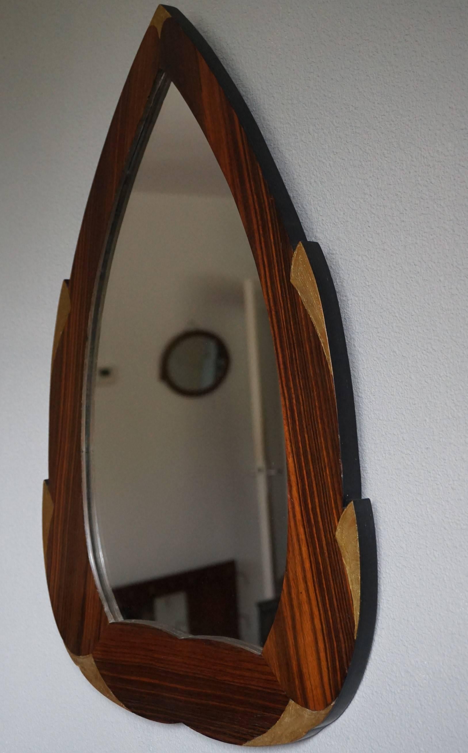 Glamorous and practical French Art Deco mirror.

This handcrafted, Art Deco mirror from the 1920s is beautiful in shape and design and it is also practical in size. The cocobolo wooden frame comes with hand-painted, golden color style elements and