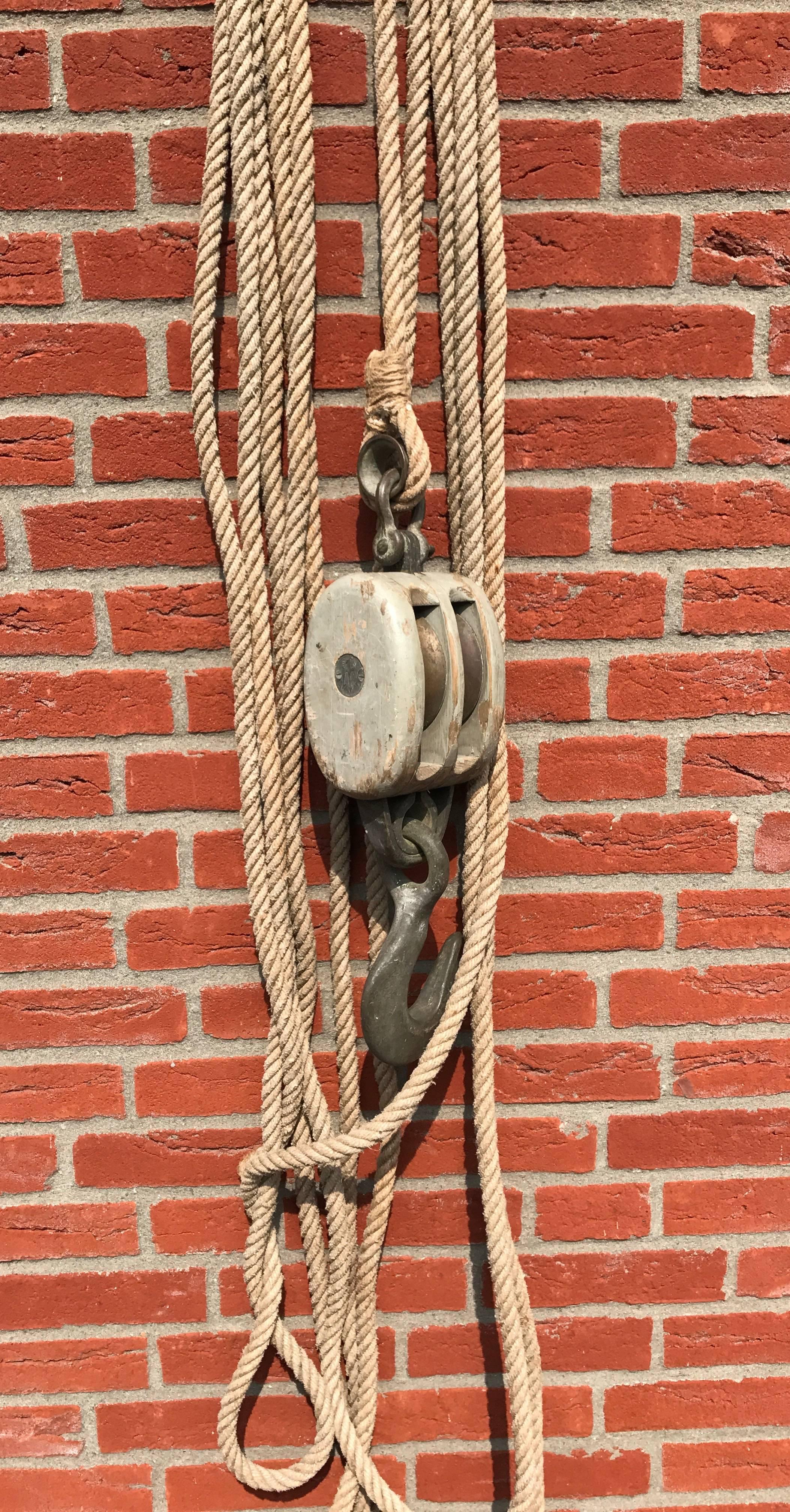 Decorative Industrial pulley for holding up your chandelier or other work of art.

This vintage and great looking, 1950s wooden double block pulley comes with two brass wheels. The combination of the good condition, old rope and the silver-grey