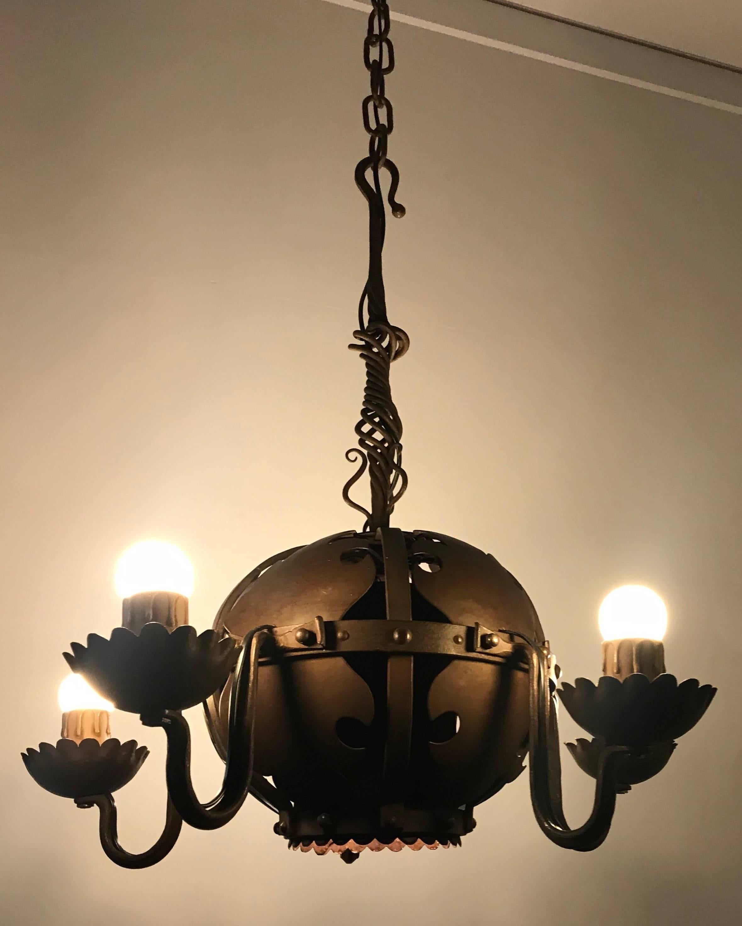 Rare design and quality crafted chandelier.

This artistic work of blacksmith lighting art is an absolute joy to watch and it is in excellent condition. The artistic details above and within the spherical centre definitely lifts it above the average