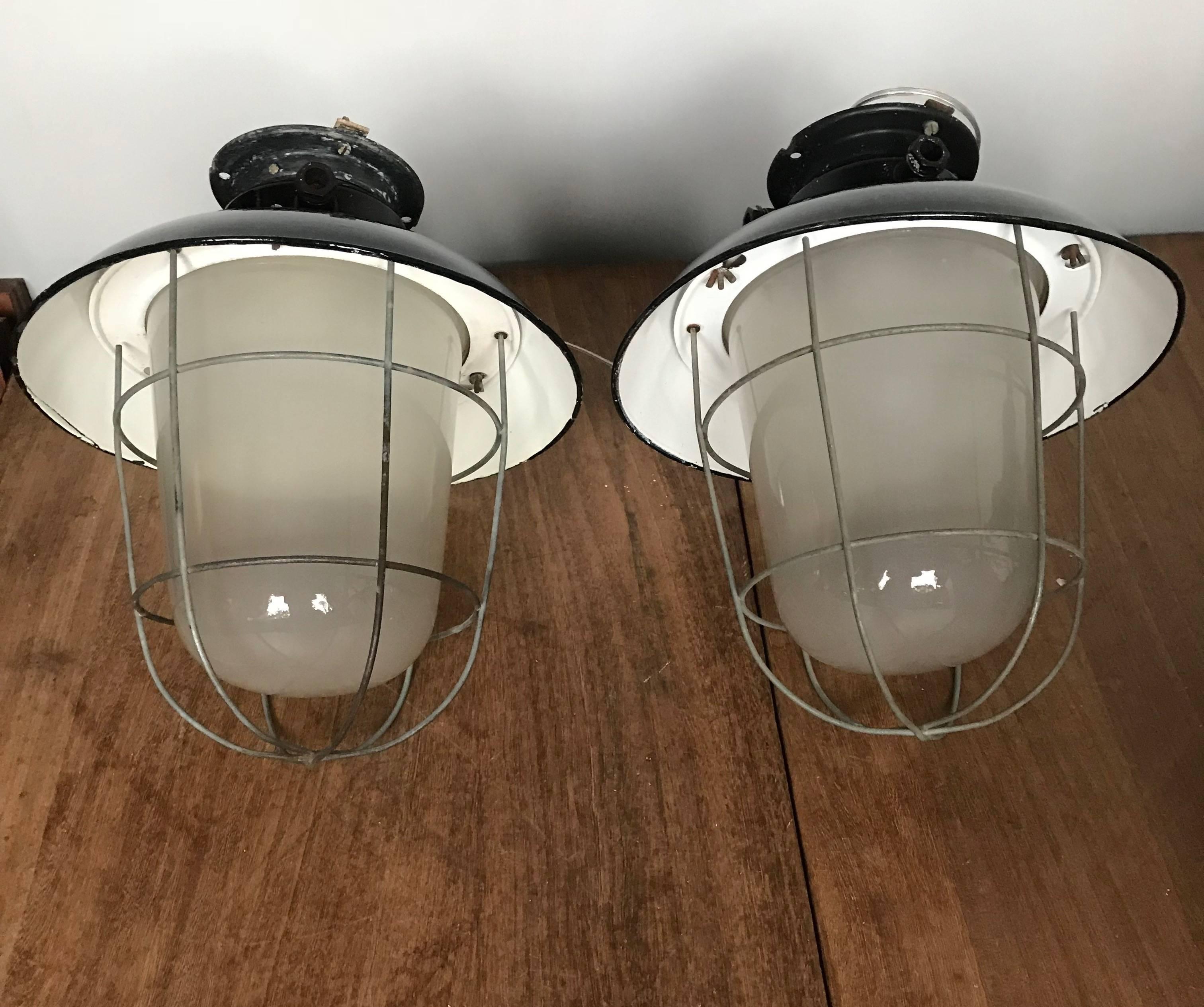 Original and great shape, industrial factory lamps. 

This rare pair of industrial pendants with its original glass shades will look wonderful over a kitchen island, but we are certain that you too can think of many other places where this cool
