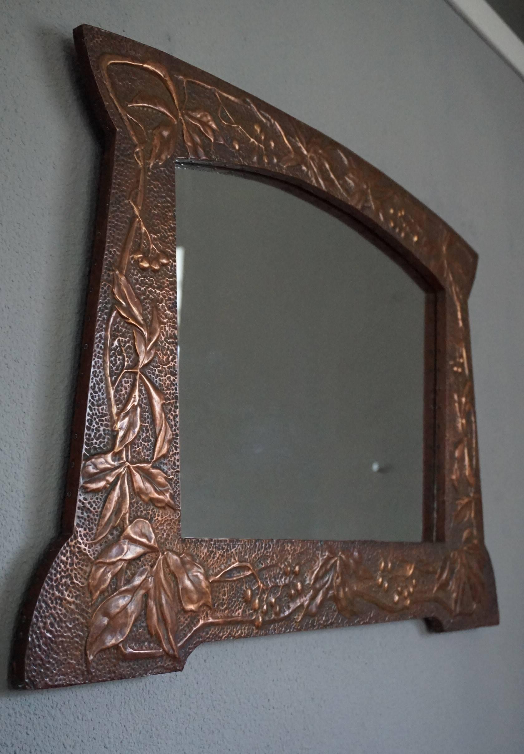Beautiful turn of the century Arts and Crafts workmanship.

This entirely hand-crafted Arts and Crafts mirror from circa 1890-1910 is in the best condition possible. The way in which the embossed and realistic leaves and berries decorate this fine
