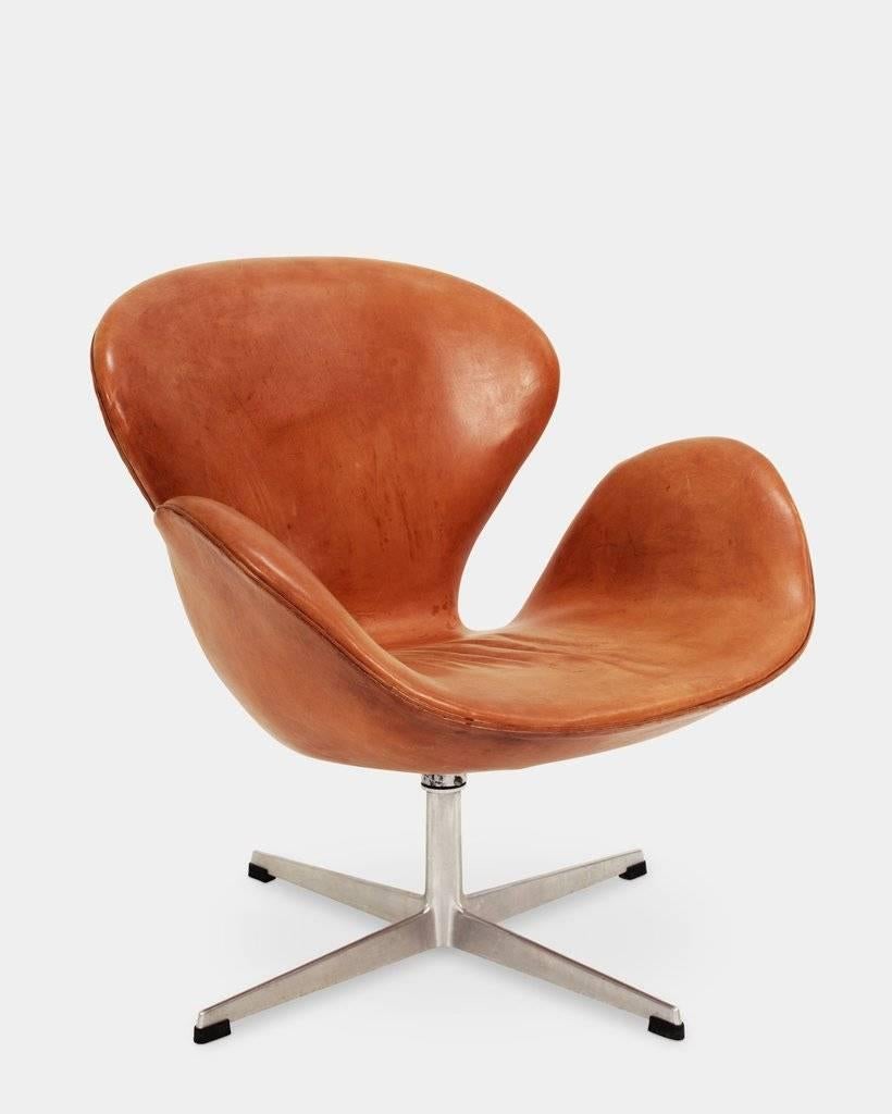 Arne Jacobsen (1902-1971) The Swan Chair, model 3322. 
Armchair upholstered in original leather with patina, swivel four-star aluminium foot, height-adjustable stem. Originally designed in 1957-1958 for Hotel Royal in Copenhagen. Early model with