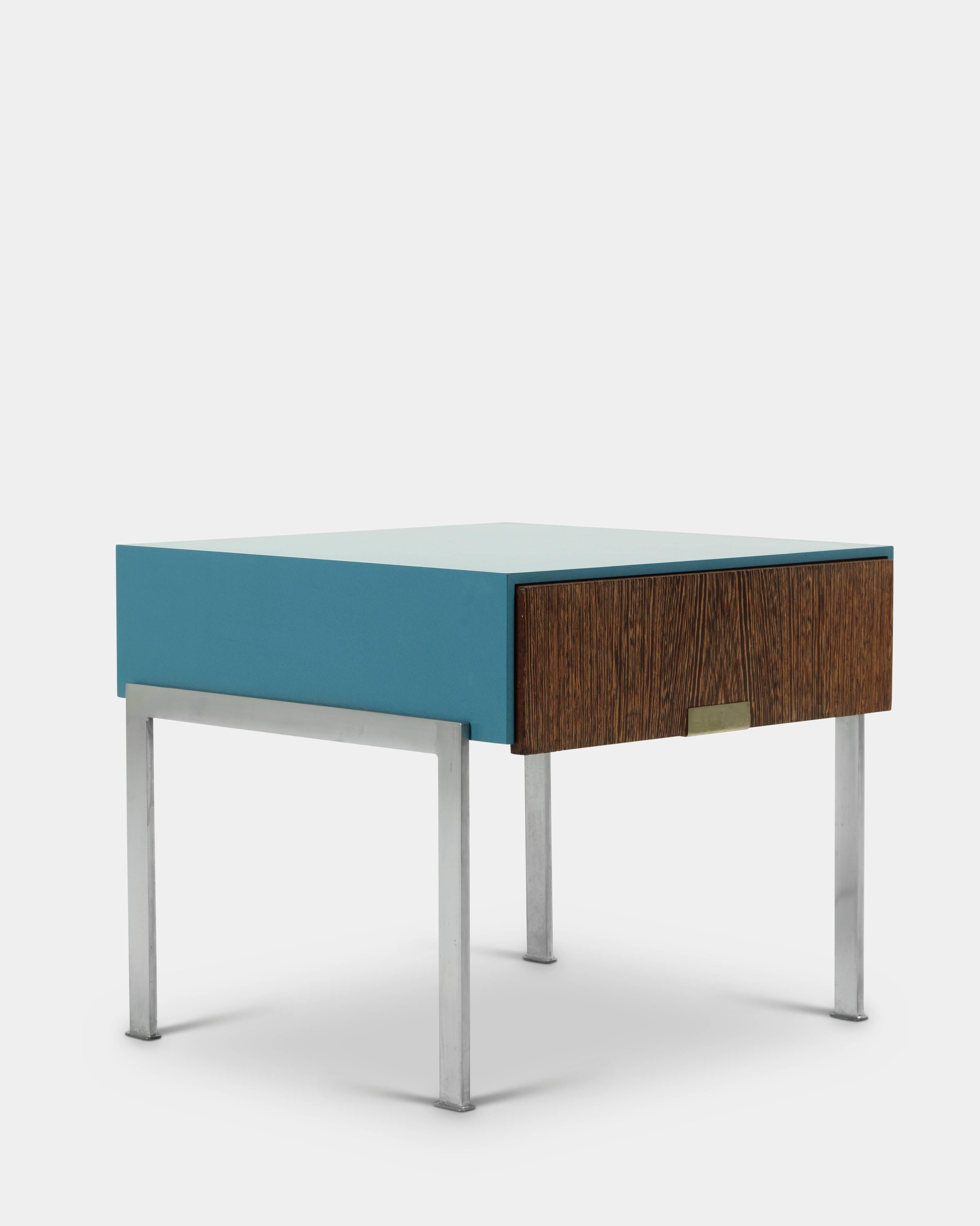 Arne Jacobsen (1902-1971):

bedside table with drawer, front and back of wengé wood, inside interior with maple veneer and sides and tabletop with blue patterned formica on a steel frame. 
Designed by Arne Jacobsen and manufactured by Fritz