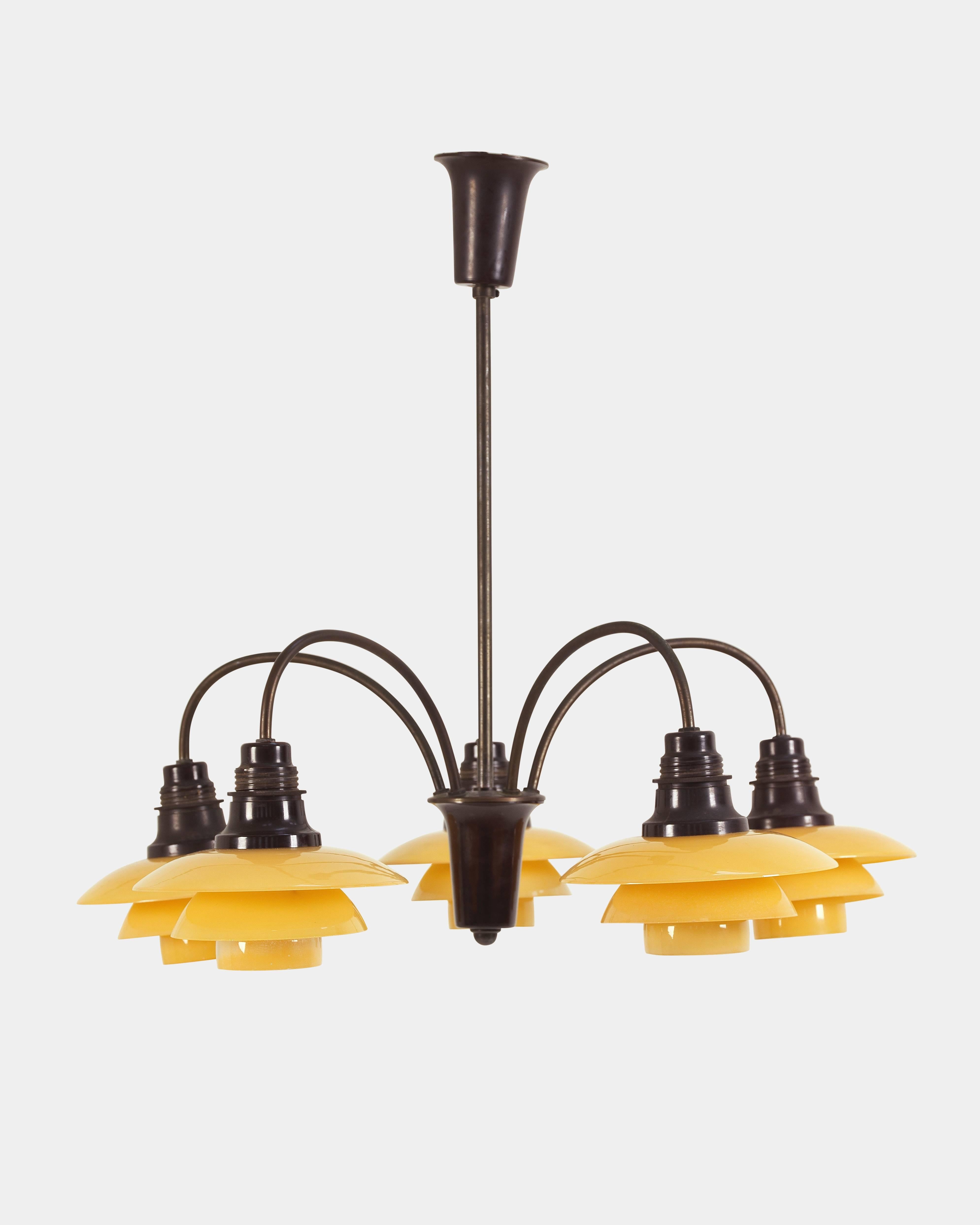 Poul Henningsen (1894-1967):
Cascade chandelier/bombardementskrone.
Five-armed, Cascade Chandelier with browned brass frame, bakelite sockets and complete 2/2 matt yellow glass shade set.
Manufactured by Louis Poulsen in the