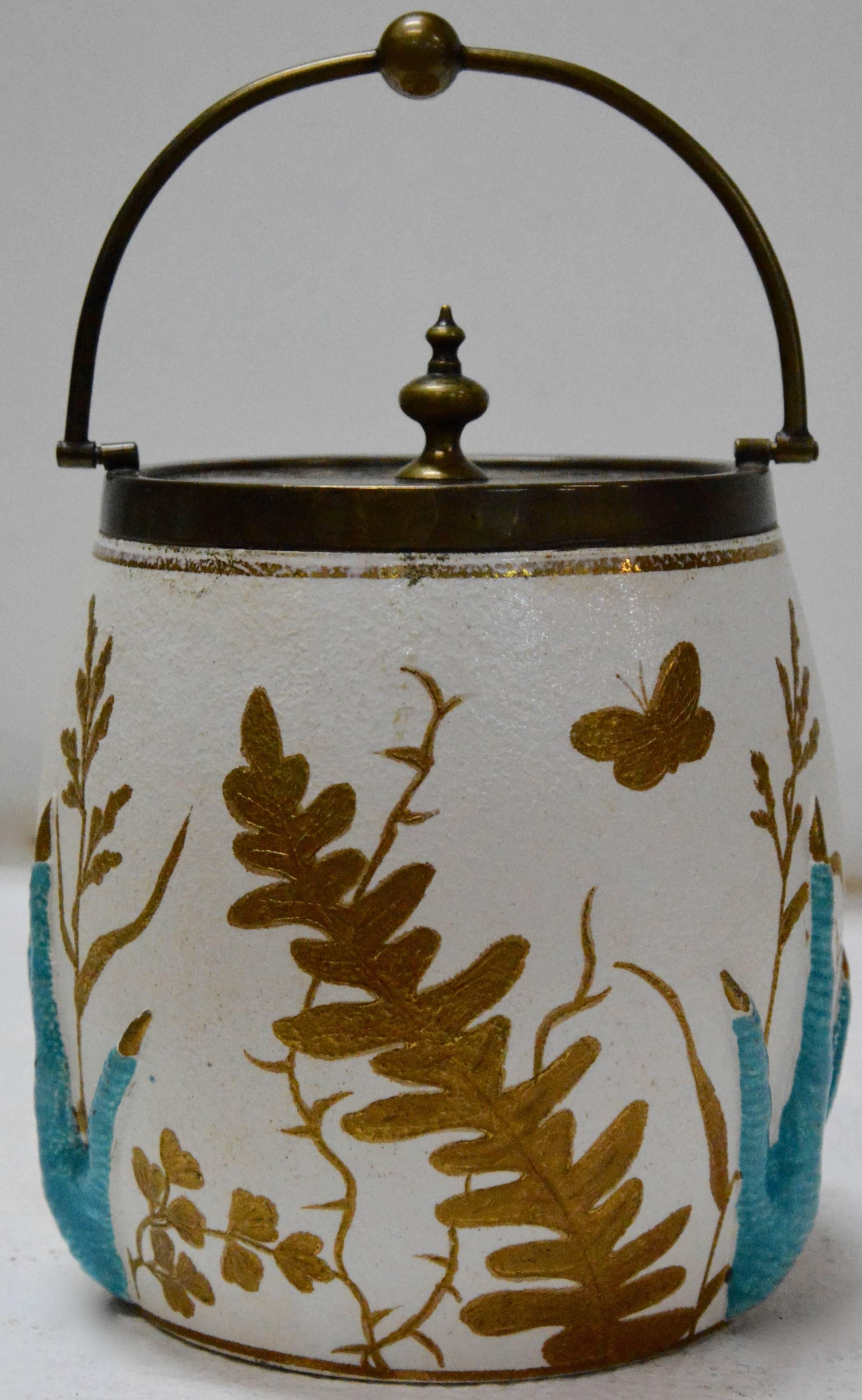 We are offering you a unique biscuit jar featuring raised turquoise crow claws amongst gold leaves on white porcelain. The top and handle are made of cast bronze with a lovely aged patina. The base is marked 3793. This is a unique piece to add to