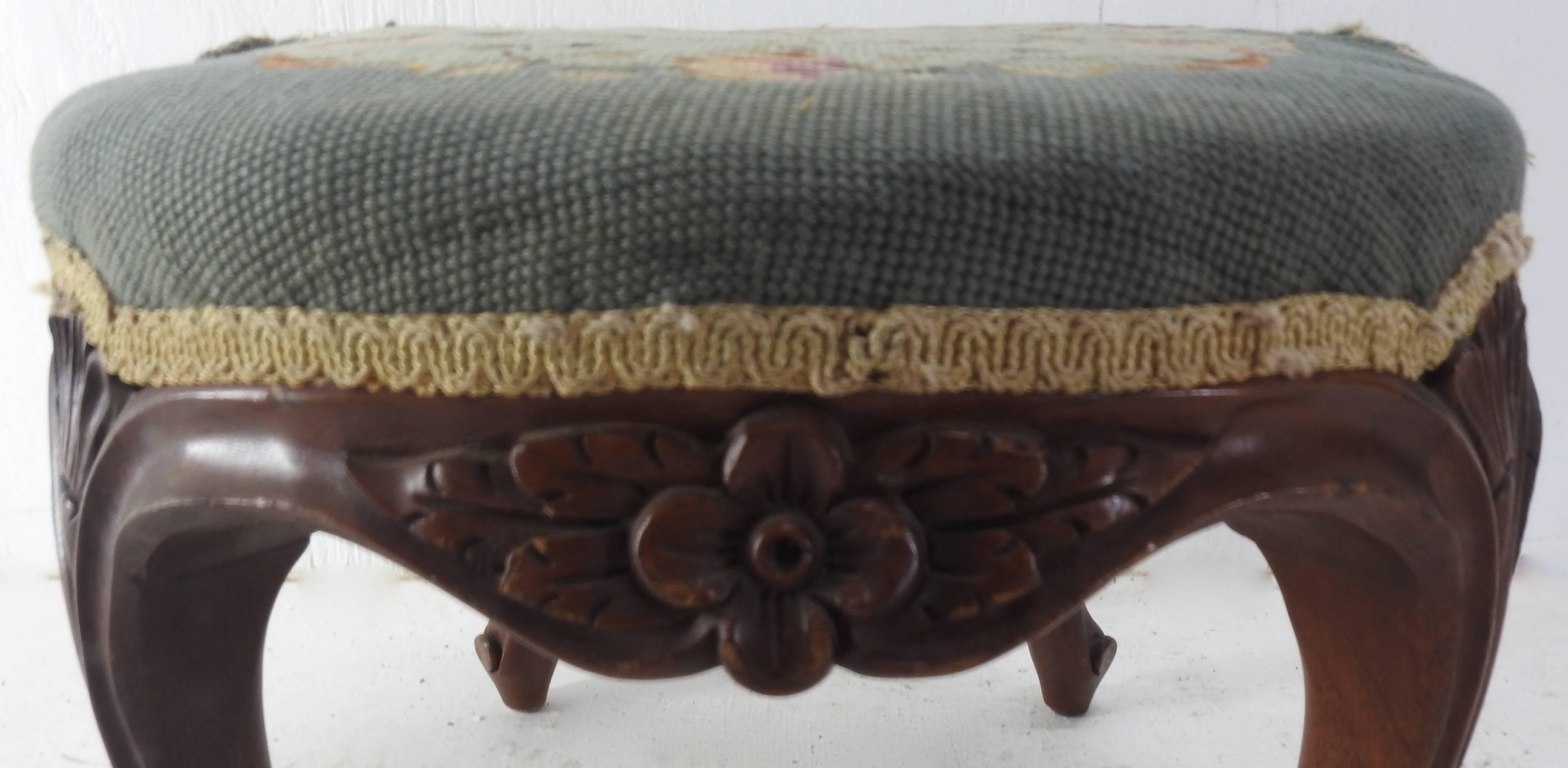 Soft flowers in a light blue centre grace the top of this needlepoint stool from America. The perimeter is done in a slightly deeper hue of blue and is surrounded by cream colored gimp. The wooden legs curve upward to support the design. There is a