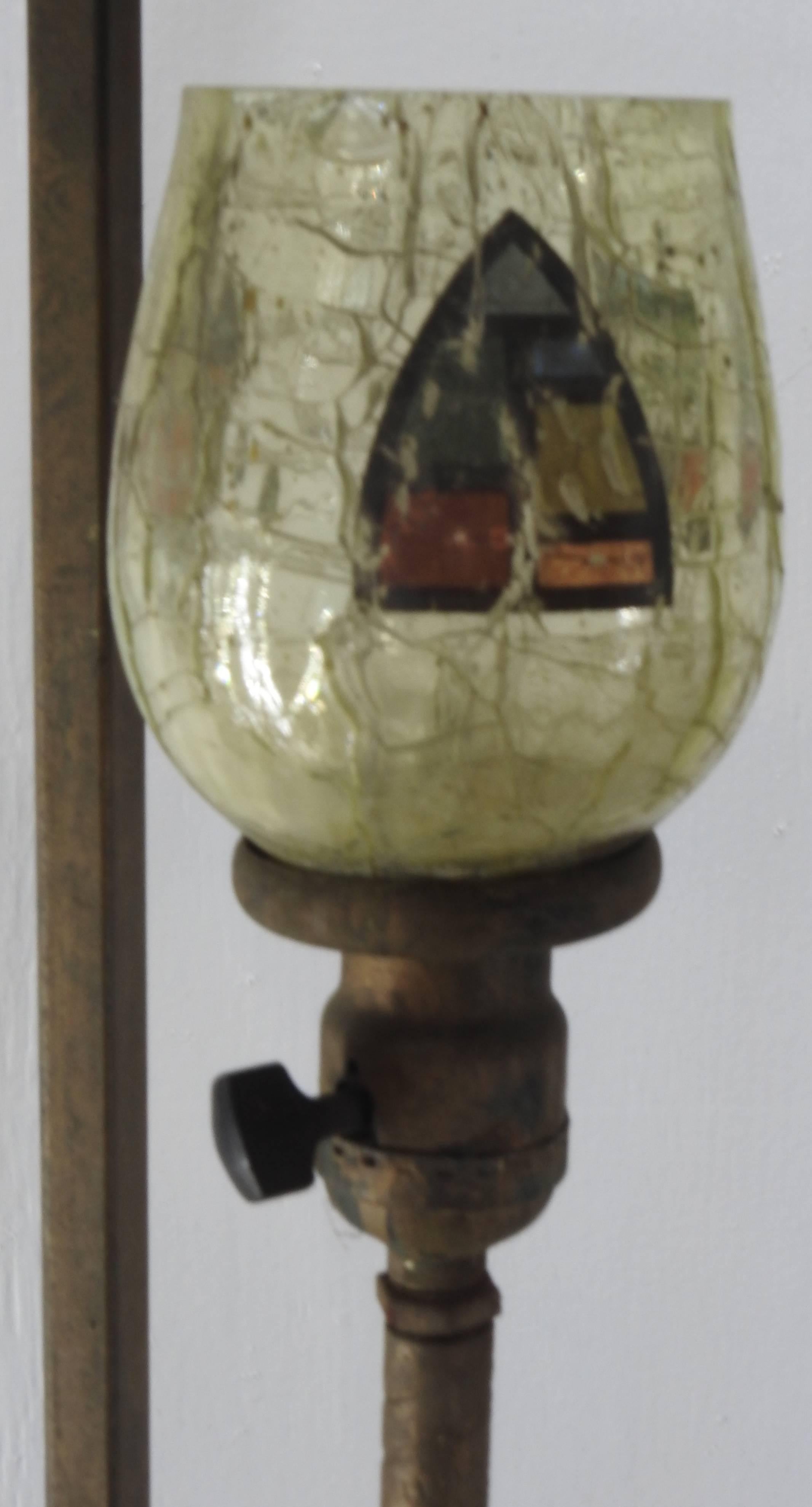 We are offering a unique lamp consisting of four arrows pointing upward. They surround a soft green crackle glass lampshade with a hand painted crest. The base is marked 