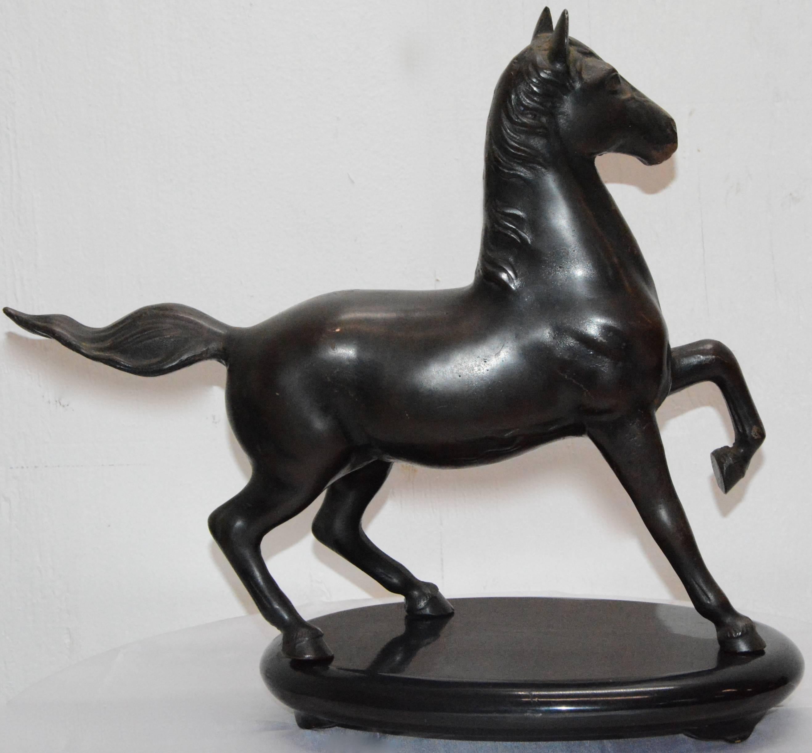This is a high stepping horse that is made of cast iron and finished off with bronze polychrome. He sits atop a black lacquer stand.