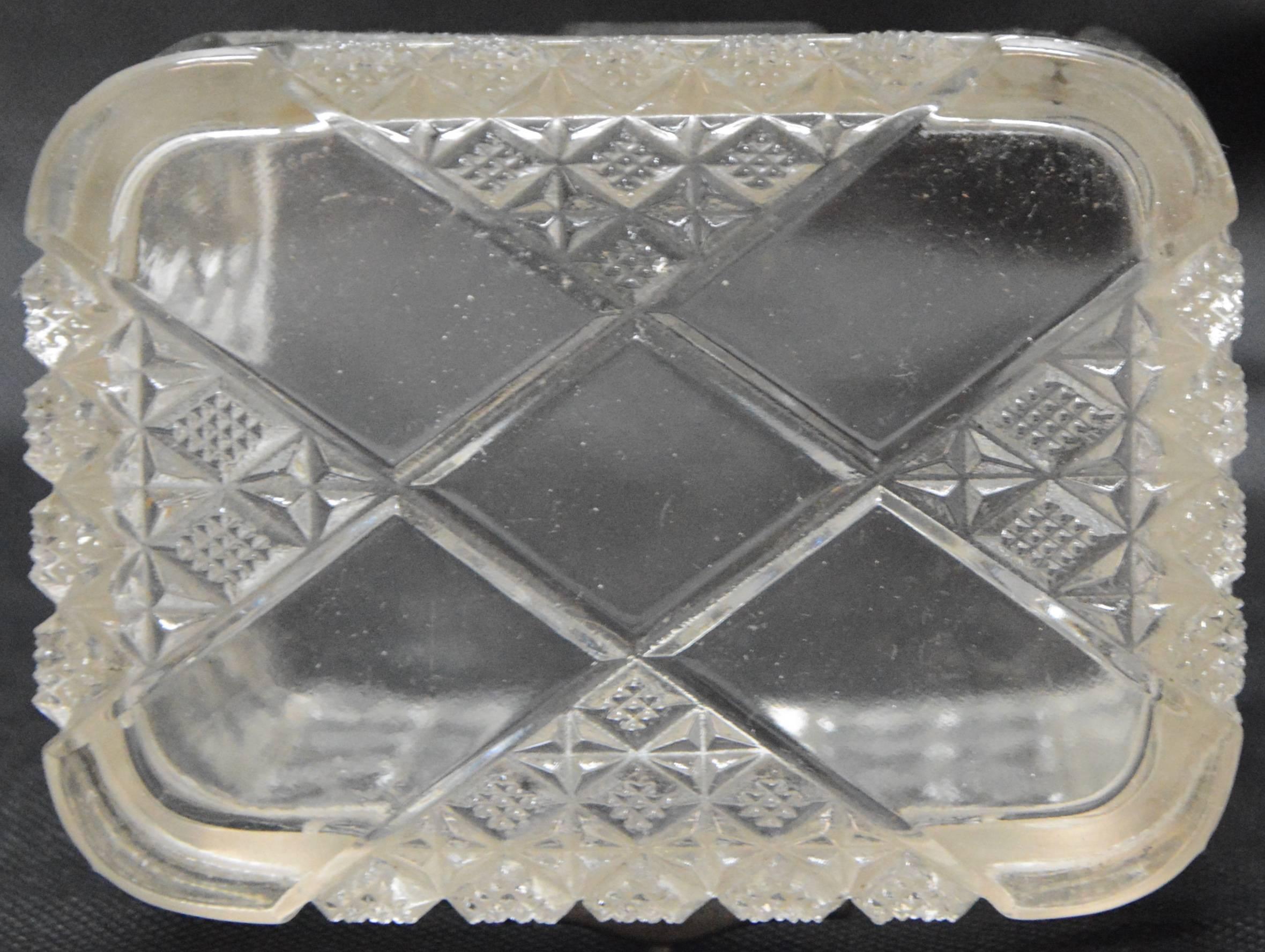 This is a stunning antique lidded pressed glass casket. The box is composed of pressed glass with panels decorated with a strawberry cut pattern throughout the exterior and silver tone panels along the corners and the closure clasp. It appears the