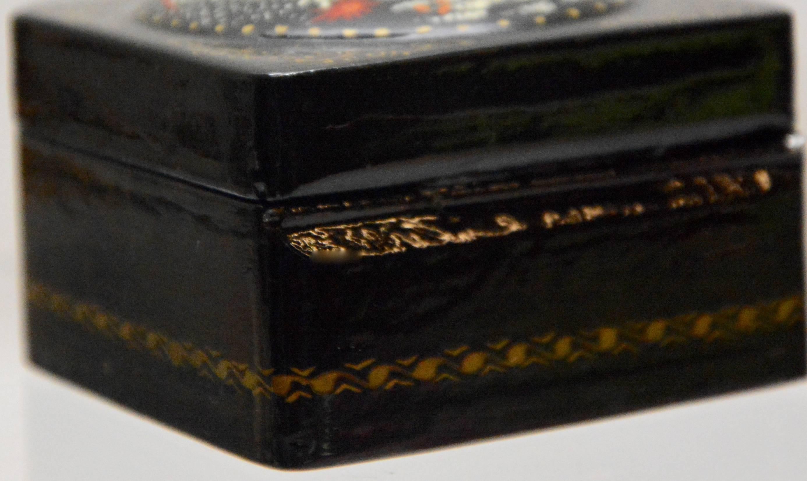 A lovely winter scene is hand painted on this hand painted Russian lacquer box. The black is enhanced with gold detailing and the interior has a vibrant red finish. The piece is signed underneath the winter scene.