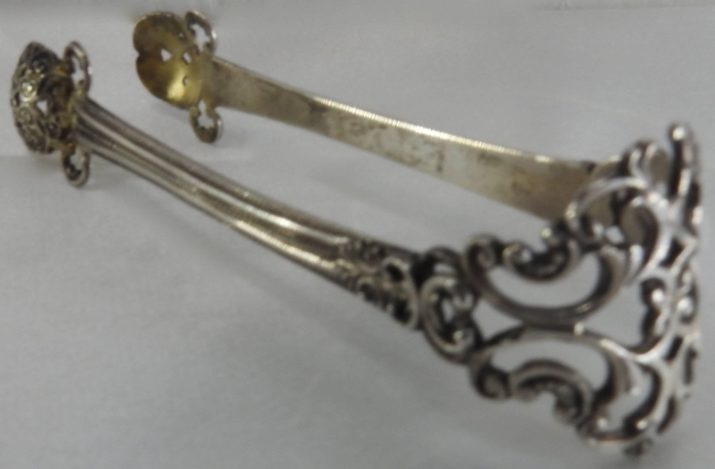 A delicate pair of vintage sterling silver tongs. This pair of small ice tongs features pierced accents and milgrain detailing marked “Sterling” to the centre.
 