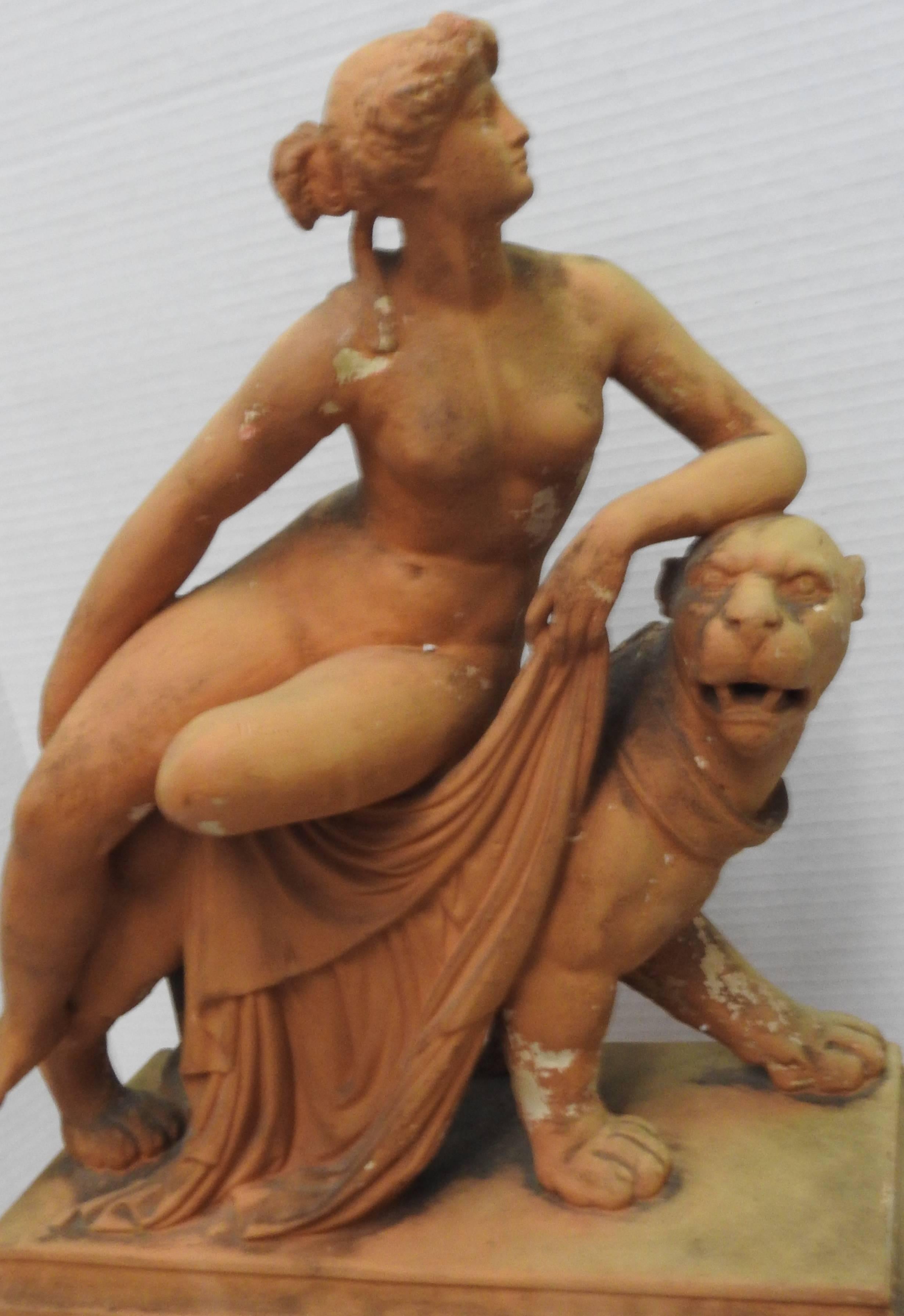 This is a stunning terracotta figure of Ariadne reclining nude on the back of a stylized panther, moving towards the right. She wears an acanthus wreath on her head, her left leg tucked beneath her right, holding drapery in her left hand, her left