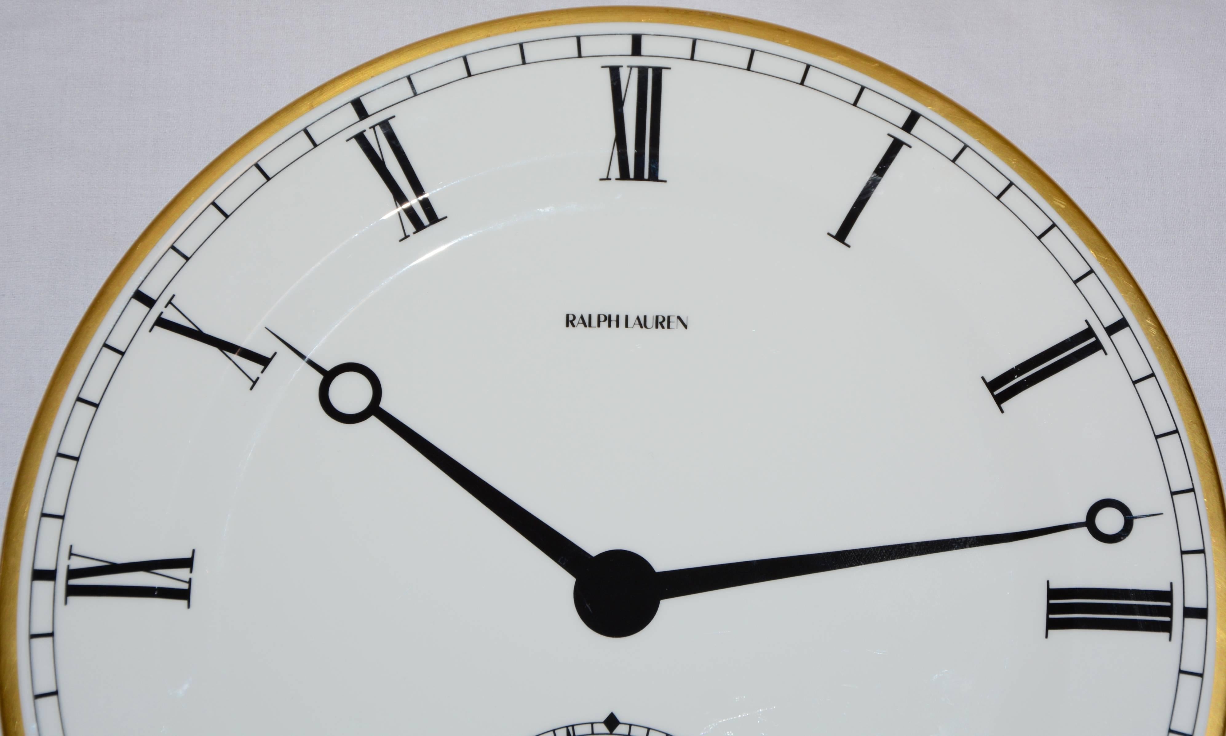 This listing features a sought after round white porcelain plate by Wedgwood for Ralph Lauren in the pocket watch pattern. This plate has a gold rim and is designed to look like the face of a watch with ebony black hands and Roman numeral markers.