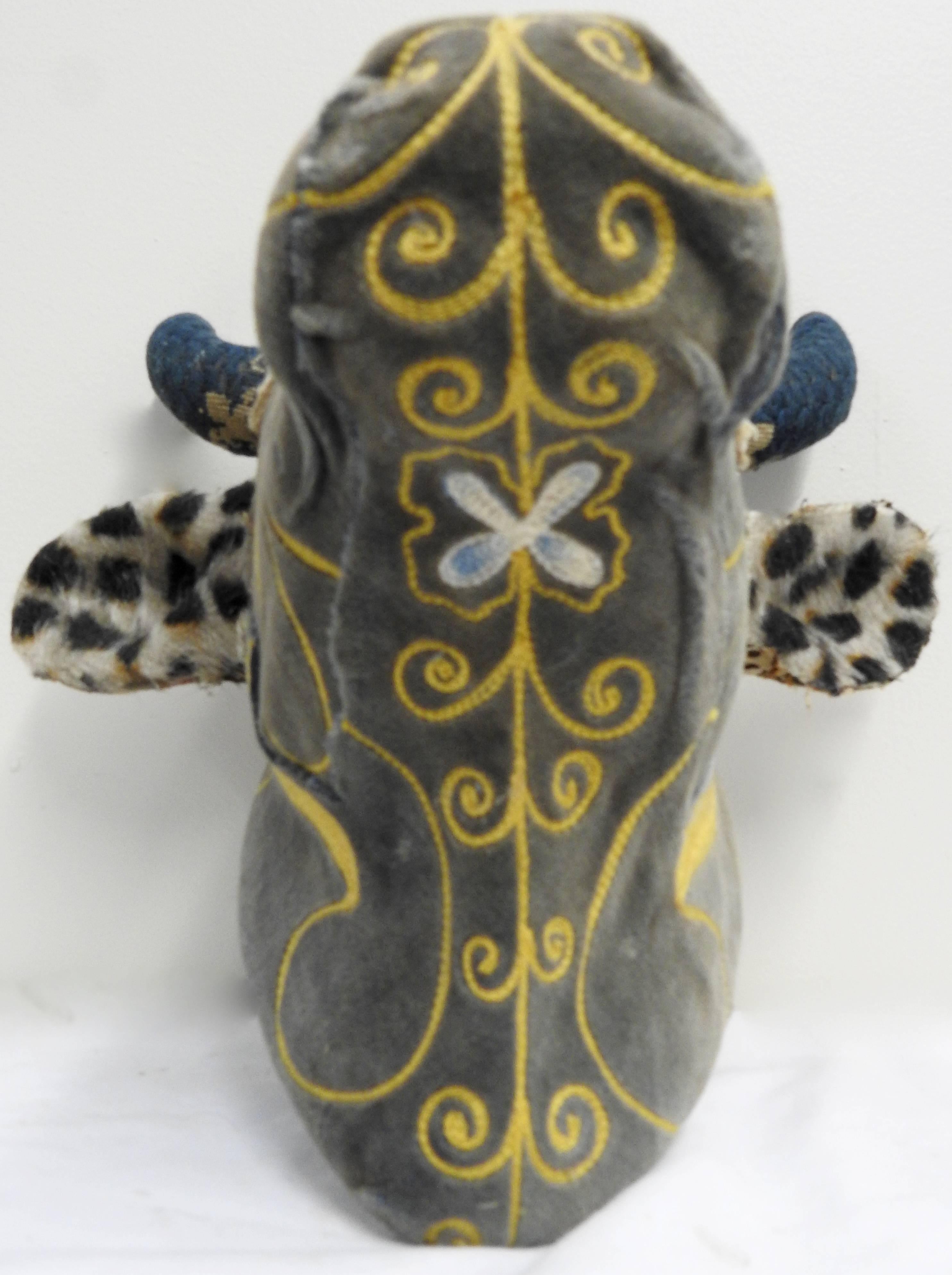 An exquisite porcelain wall mount heifer that sports a variety of vintage and antique textiles. The main part of her face is a soft velvet with beautiful embroidery. The front part of the ears are covered with an animal print fur. The backs of the
