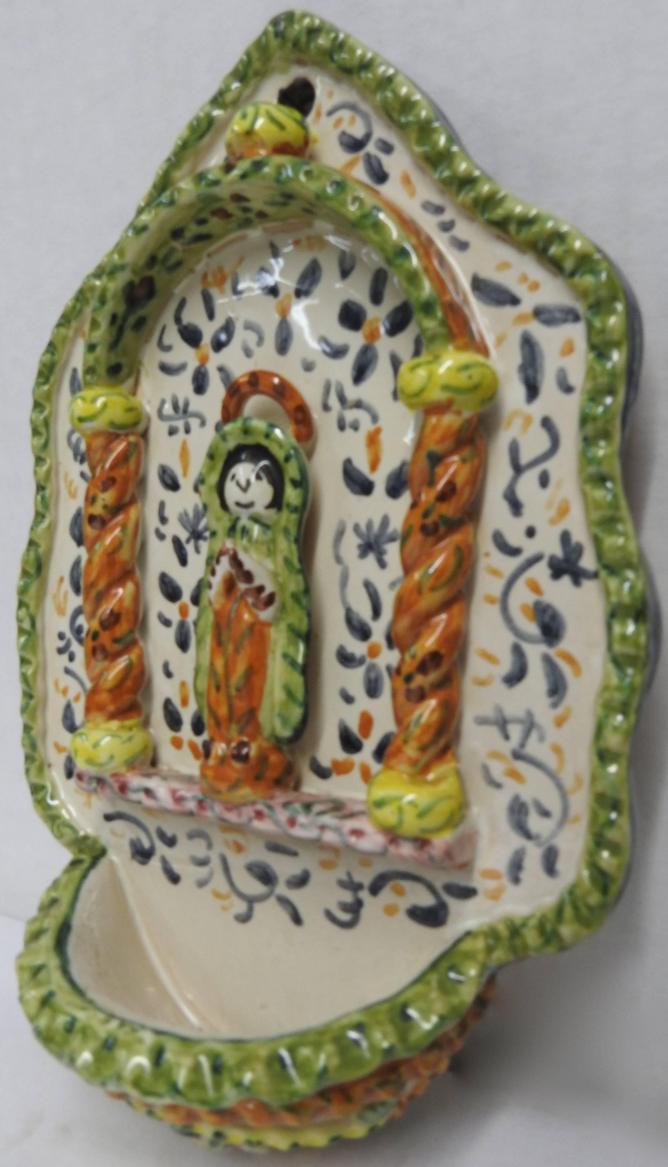 A simple angel stands in the center of this hand painted ceramic Holy water font. The angel is surrounded by a variety of lovely colors. The Artist-signed the piece on the inside of the font.