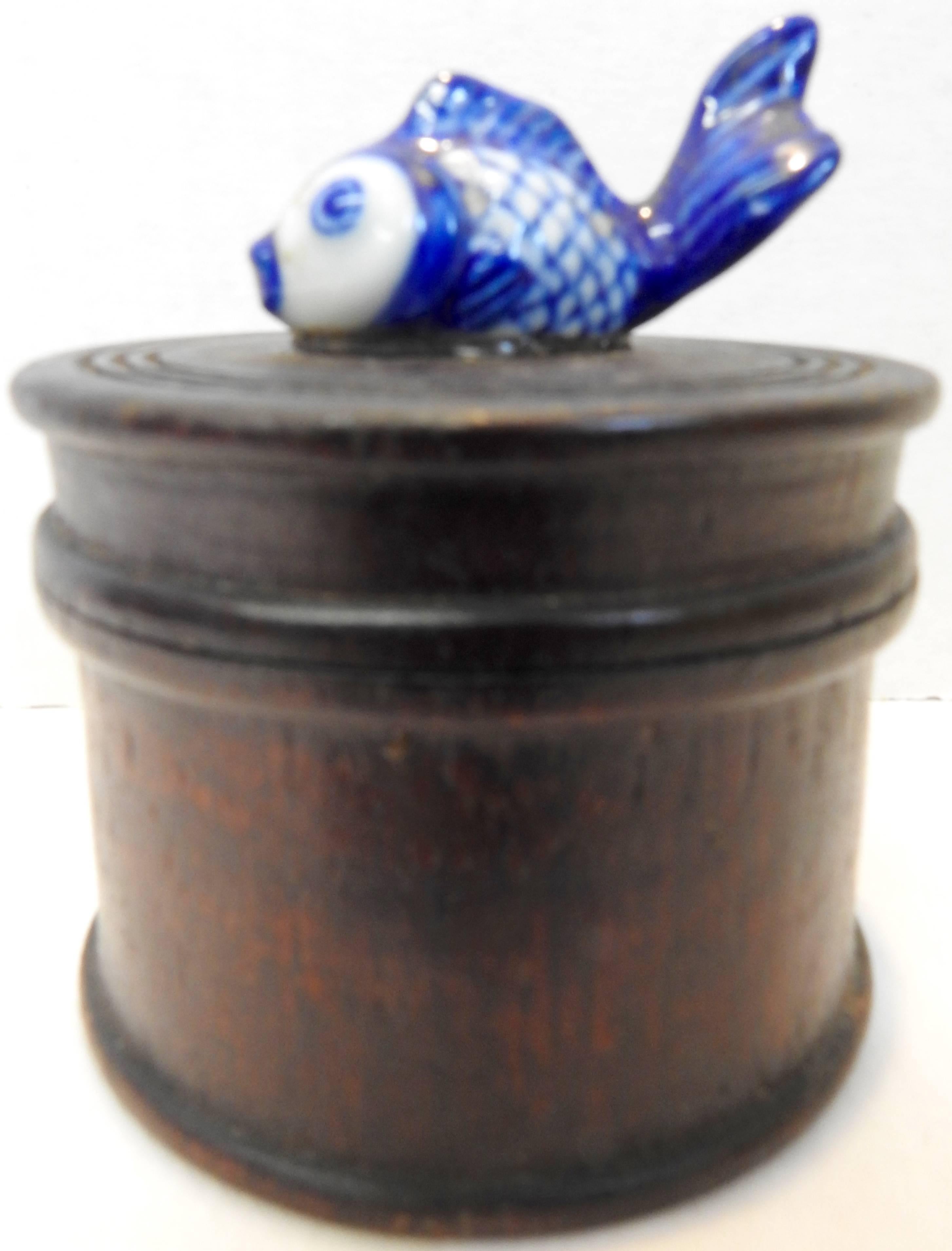 A hand painted porcelain koi fish is perched on top of the lid of this round wooden box. The lid comes off for you to store your treasures inside.