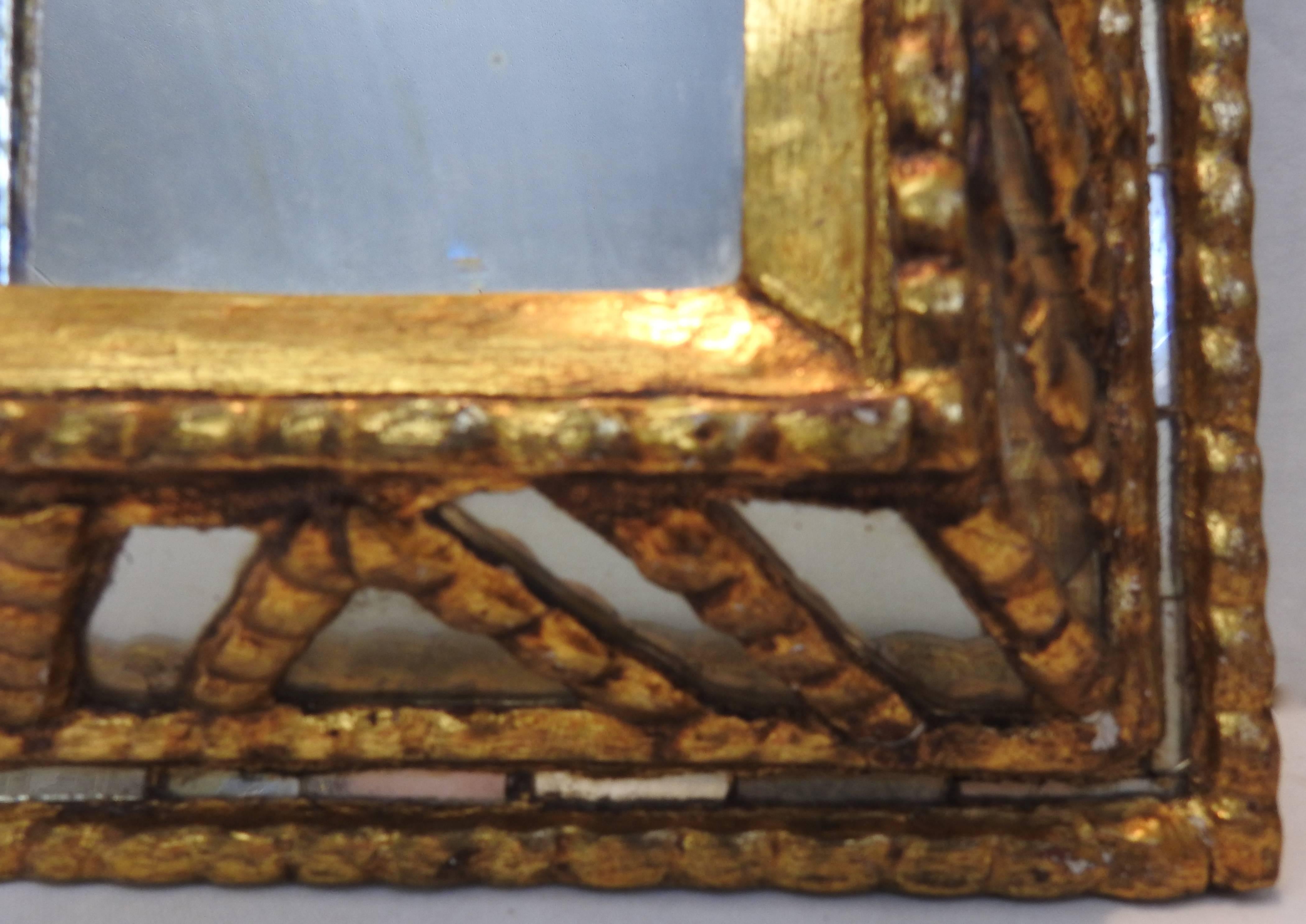 Featured is a unique mirror with panes of silvered glass surrounded by distressed gilt over gesso. The different dimensions will catch your eye as you walk by. A metal loop is mounted on the back for hanging.