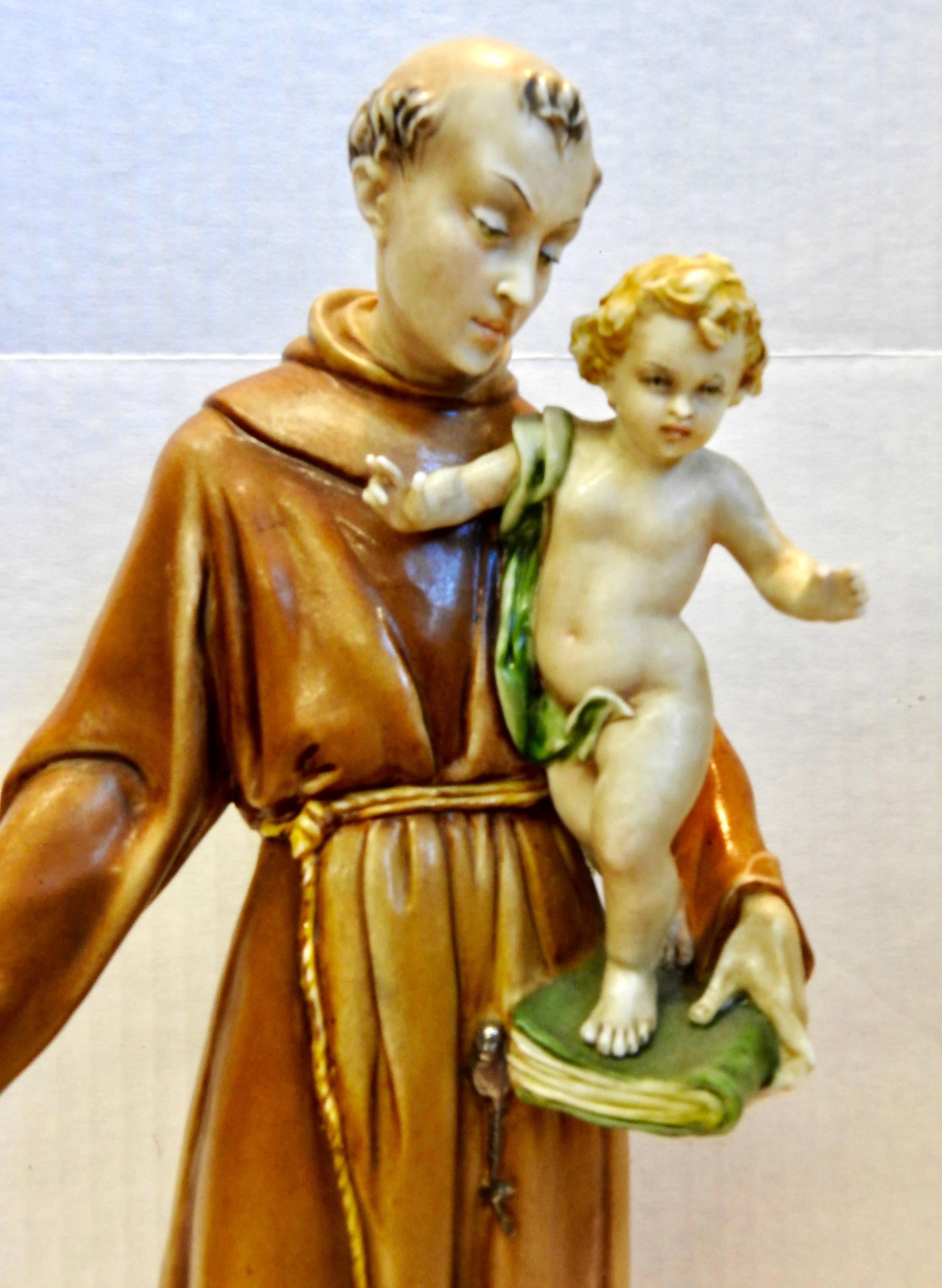 Saint Anthony is holding a cherubic child on his book and is looking at him lovingly. The porcelain has been glazed in soft colors. The figurine is marked in the back and on the bottom.