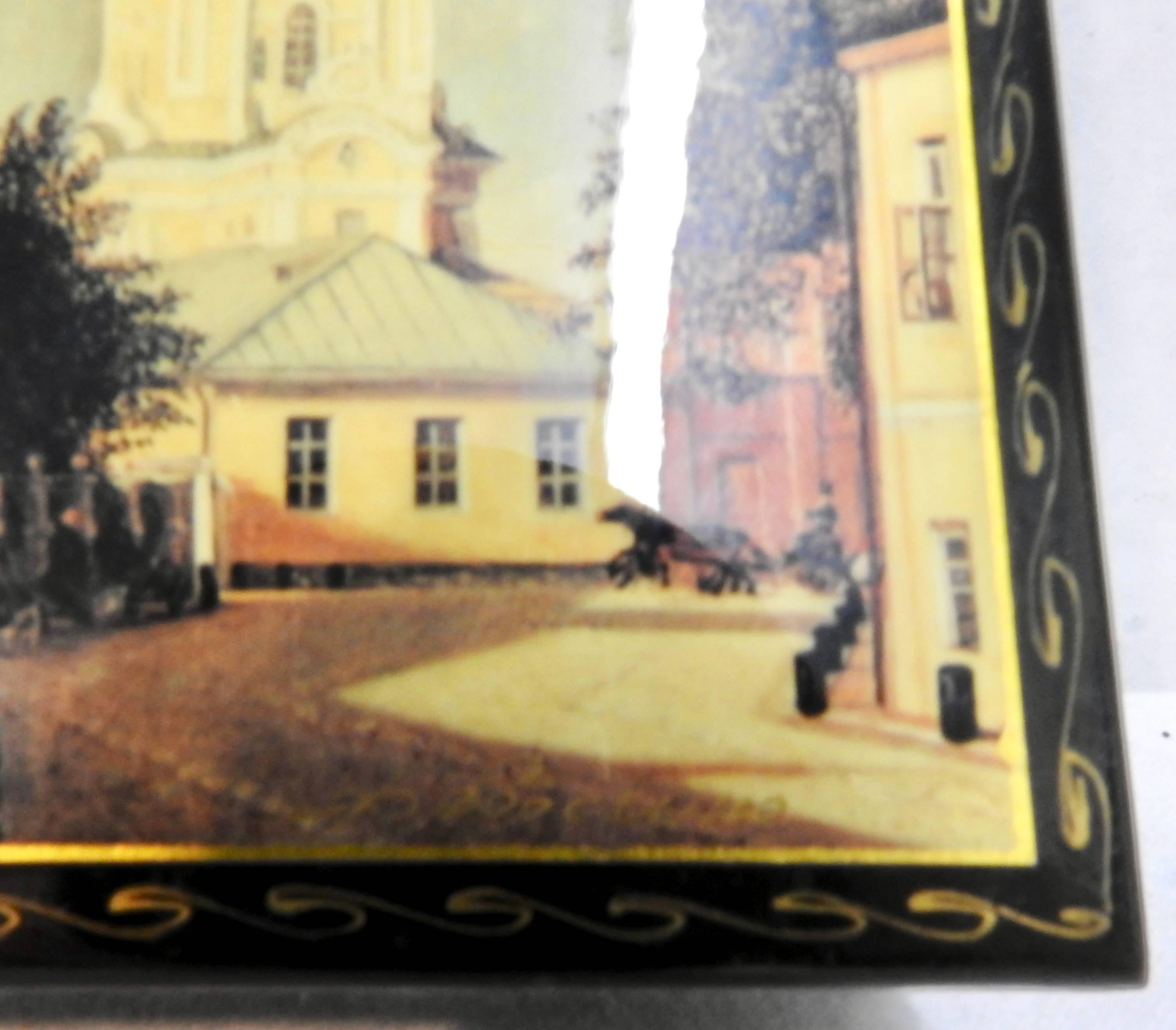 The edges of this black lacquer box from Russia have been decorated with waves of gold. The top boasts scenes of buildings near the Kremlin with elegant architecture. The box has been signed but we could not identify the artist. The top opens to a