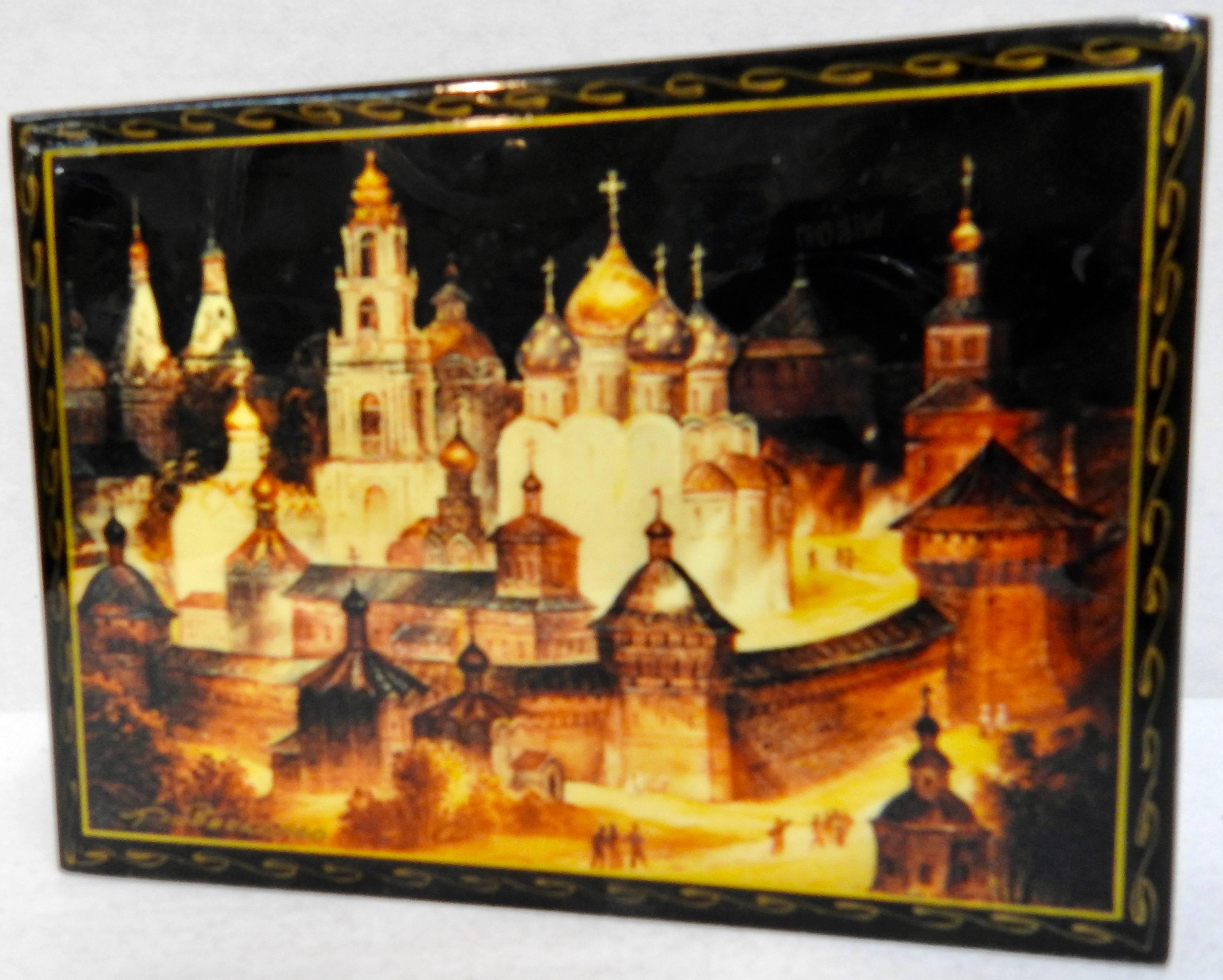 Elaborate architecture is displayed on this Russian black lacquer box with a vibrant red interior. It features the Kremlin and red square in Moscow. The lid has been signed but we could not identify the artist. Waves of gold embellish the edges of