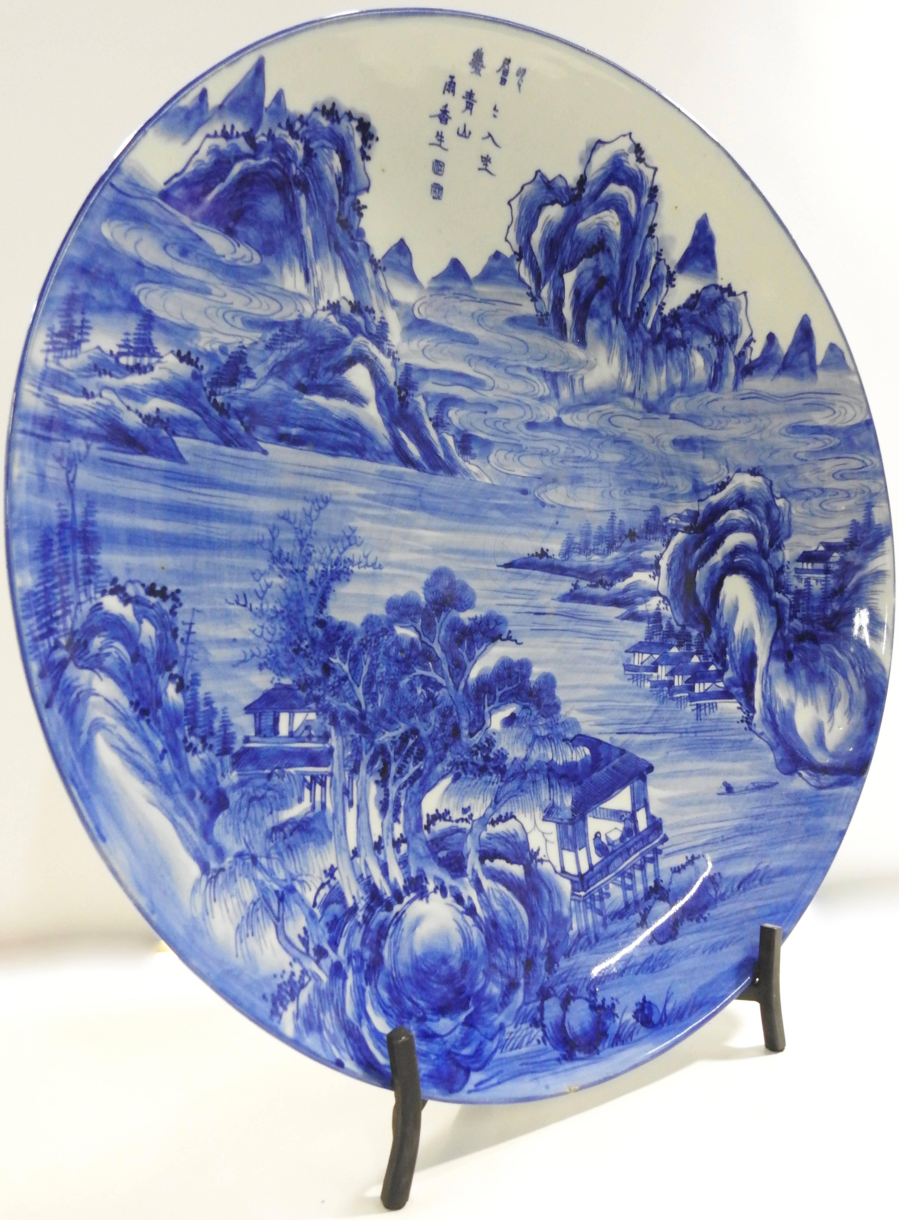 We are offering a massive hand painted blue and white plate from China. A swirling water scene flows through the mountains and Classic buildings are surrounded by trees. The back of the plate has ribbons of flowers along the perimeter. The piece is