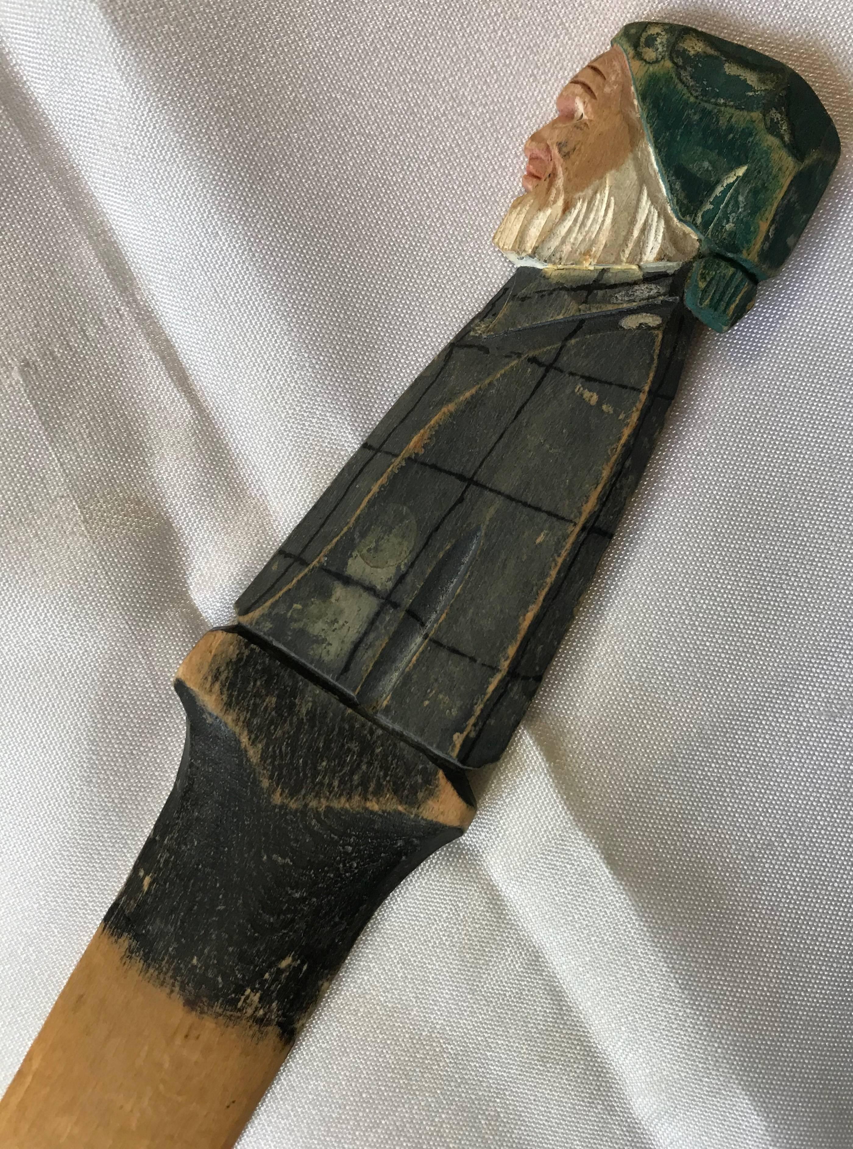 This vintage hand carved wooden letter opener boasts an older gentleman with a white beard dressed in his night clothes. His head is topped by a green night cap and he wears gray with black pajamas.
