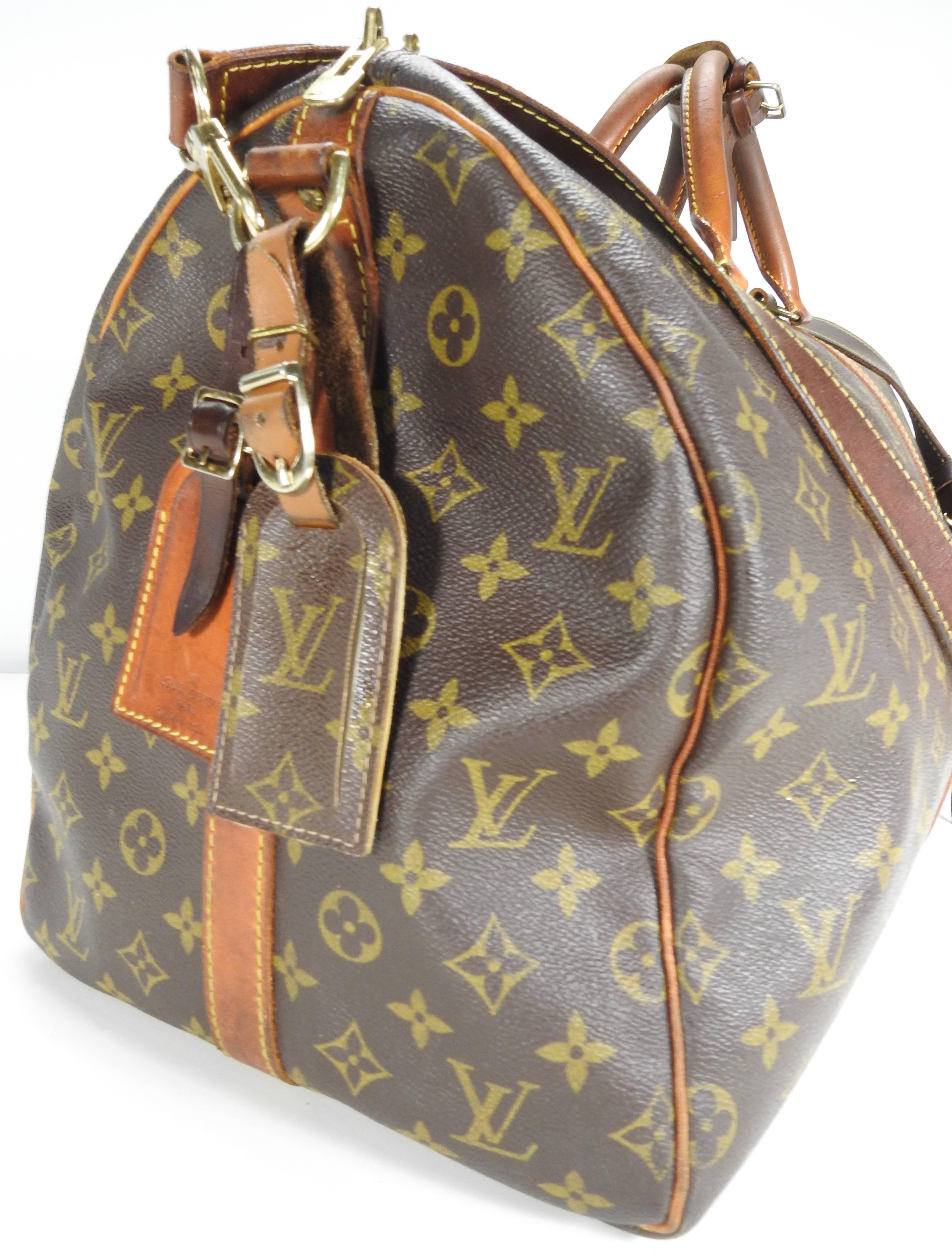 Featured is a Classic Louis Vuitton Keepall leather travel bag with the LV monogram. Top zipper with handles for carrying and a detachable shoulder strap. Two tags are attached. A leather strap with a buckle is included to attach the pair of carry