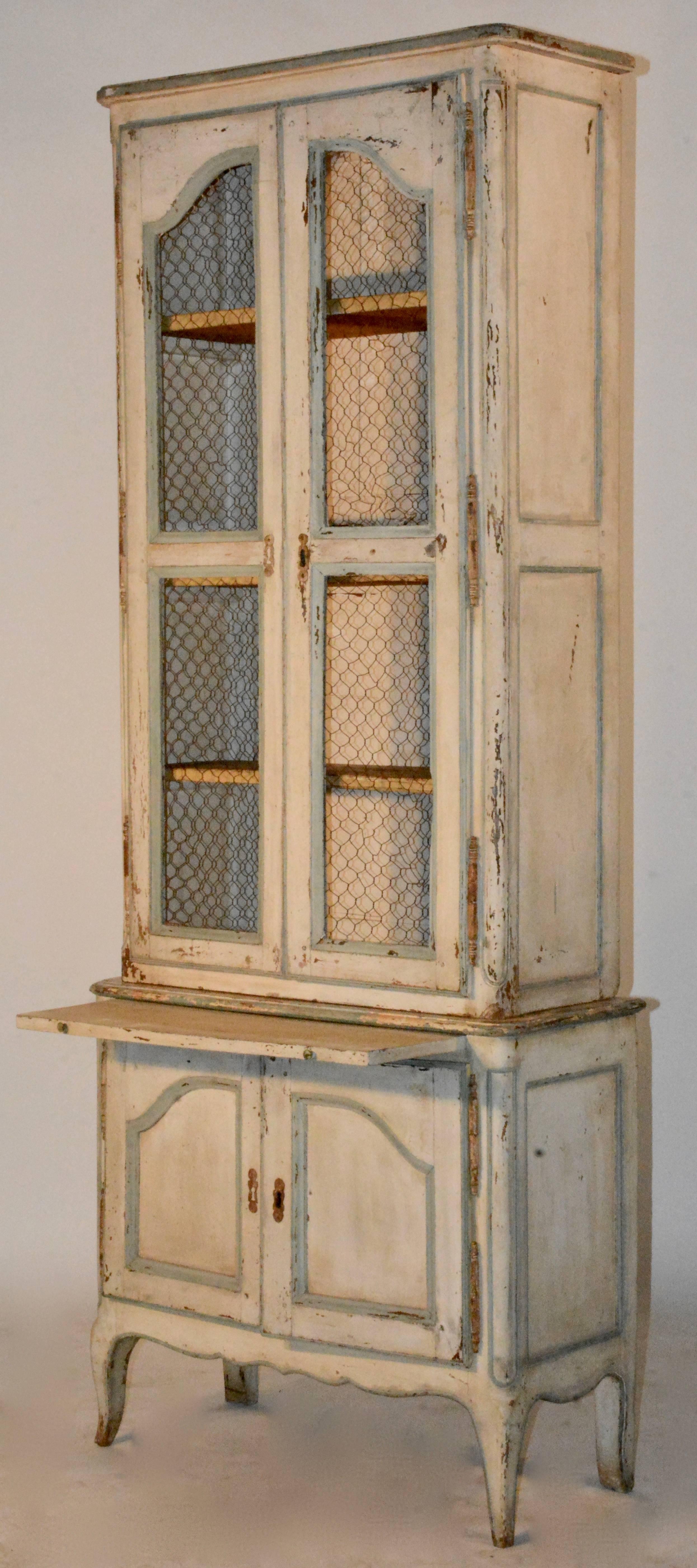 This two-piece cupboard features the original paint and wire front. Has a pull-out board. Original lock mechanisms and key. It boasts a beautiful soft cream color with blue accents. The bottom doors open to add more storage.