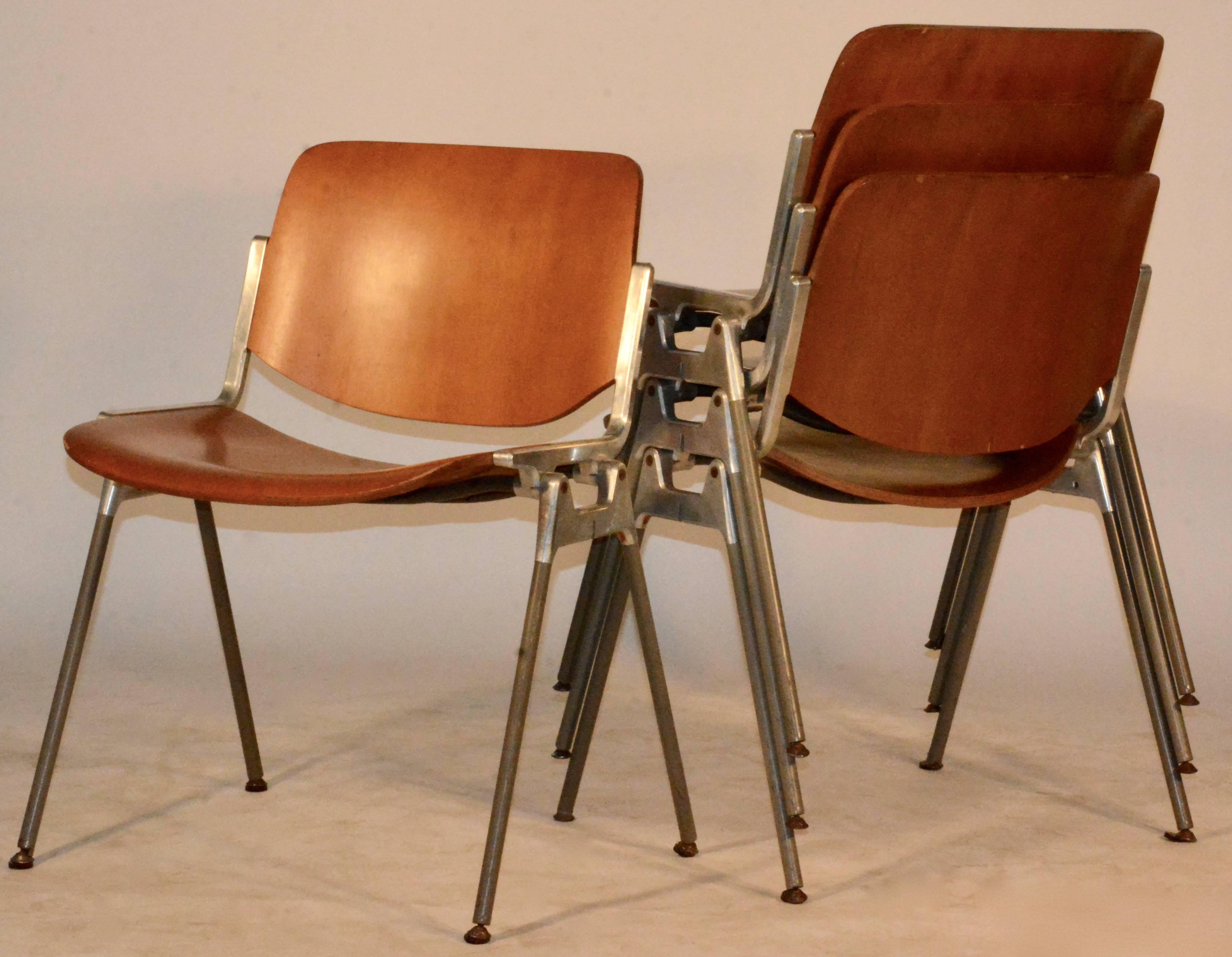 A set of four Mid-Century Modern Giancarlo Piretti DSC Axis 106 conference chairs by Castelli. These Italian stacking chairs feature carved pressed wood backs and seats stained in a warm tone. The sturdy silver tone metal frames have four tapered