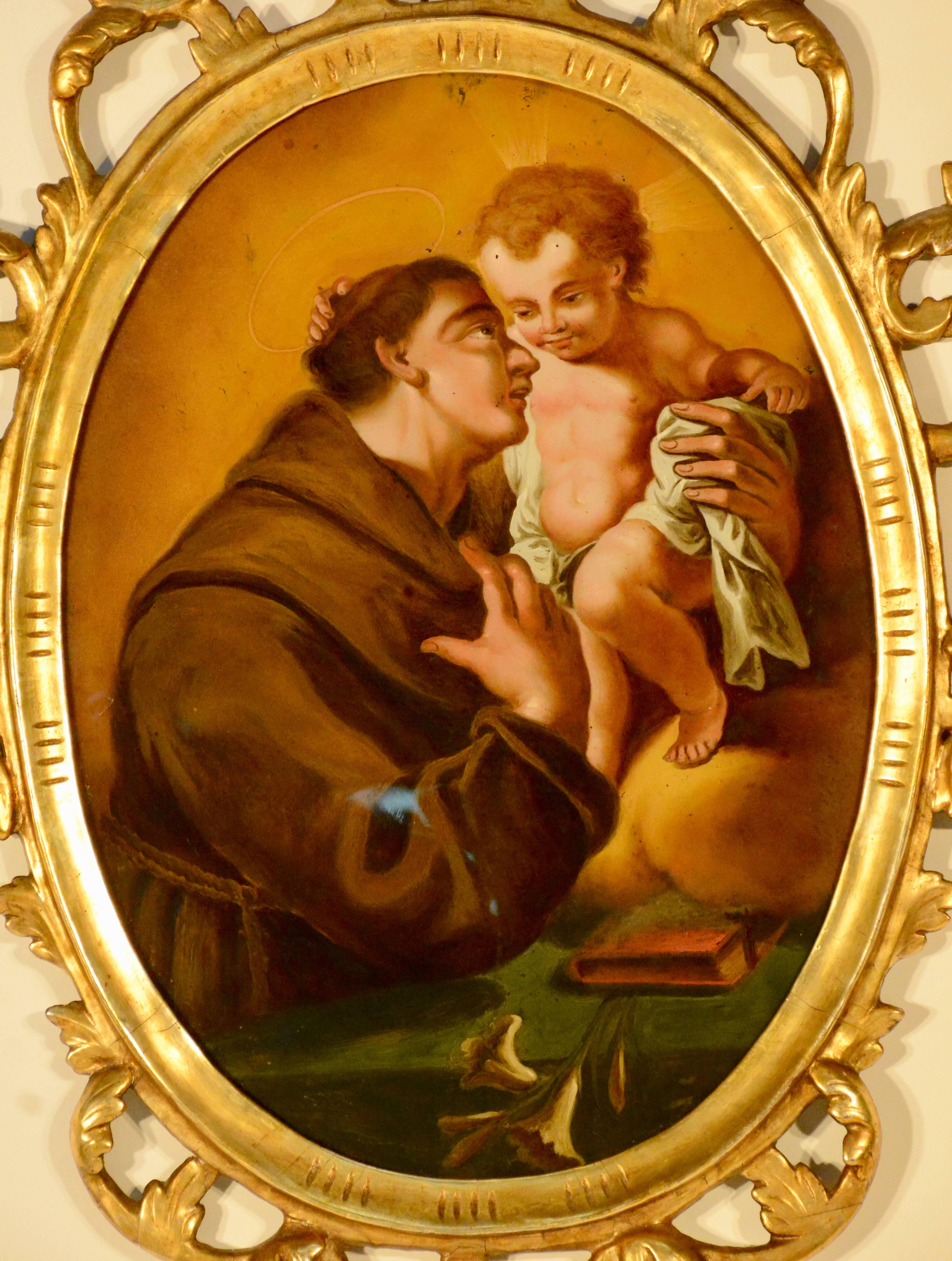 This is a Northern Spain religious reverse painting on glass depicting Saint Anthony of Padua with Child. It is enclosed by an arched, gilded wood and gesso frame and is carved with open work detail.